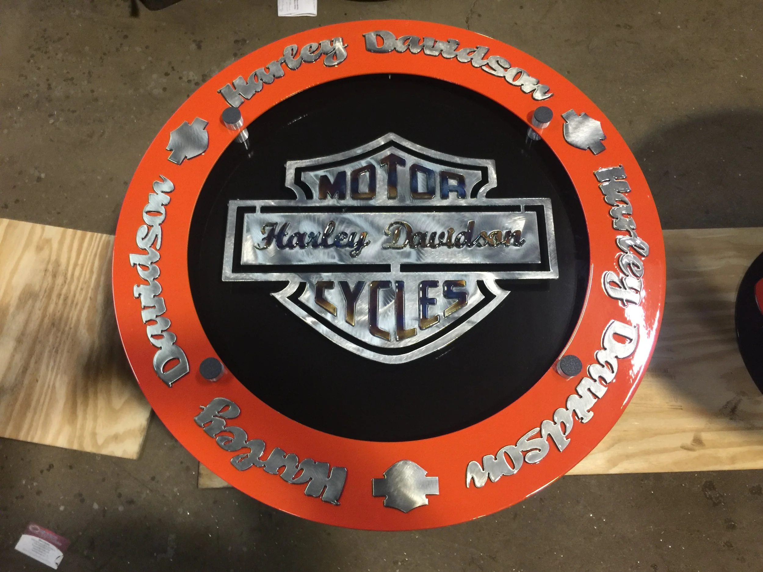 Harley Davidson Motor Cycles logo in the center, surrounded by a red circular border with silver text and symbols that say 'Harley Davidson' and 'Motor Cycles' repeated around the border.