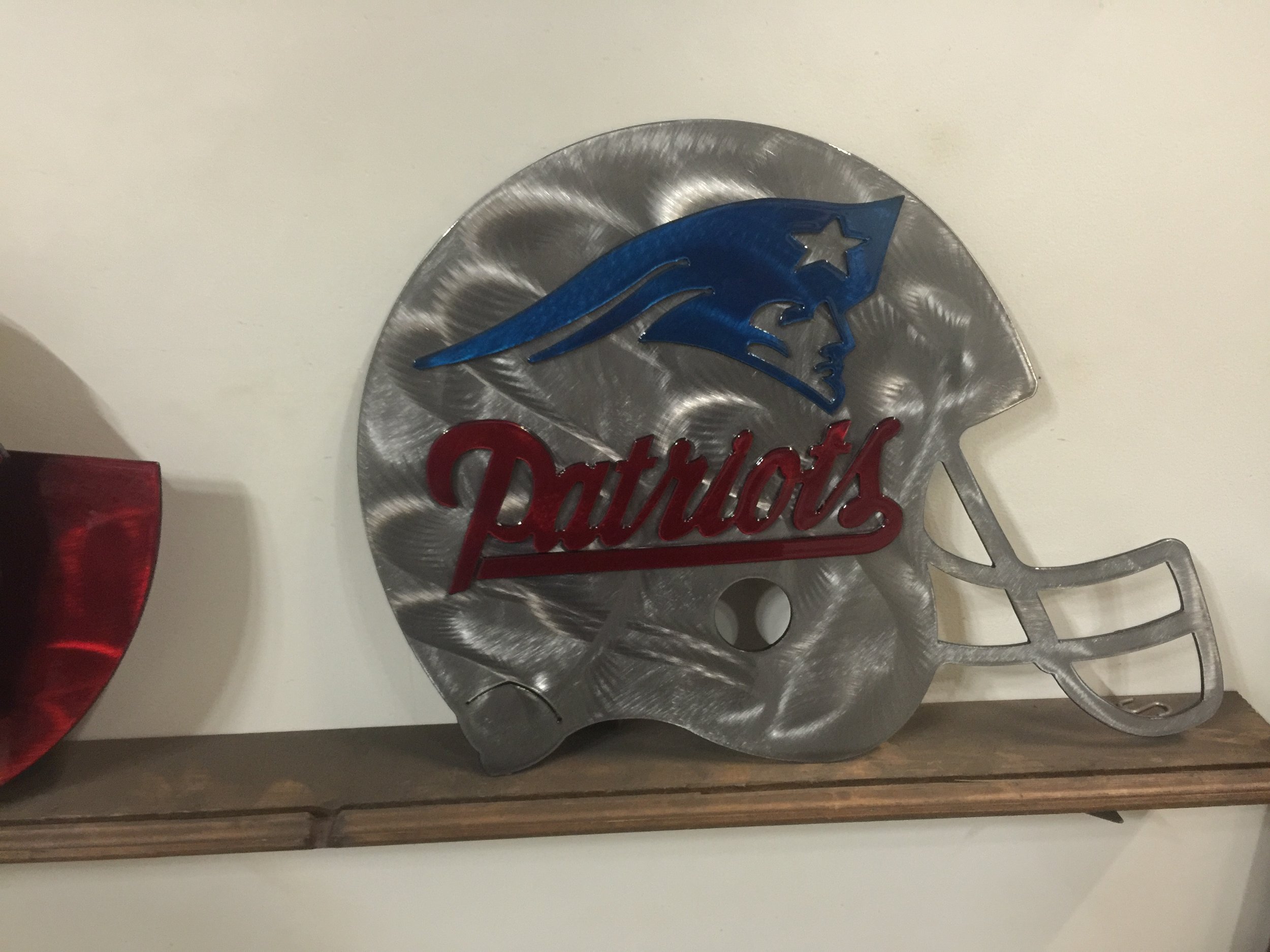 A metallic football-shaped sign with the New England Patriots logo and team name.