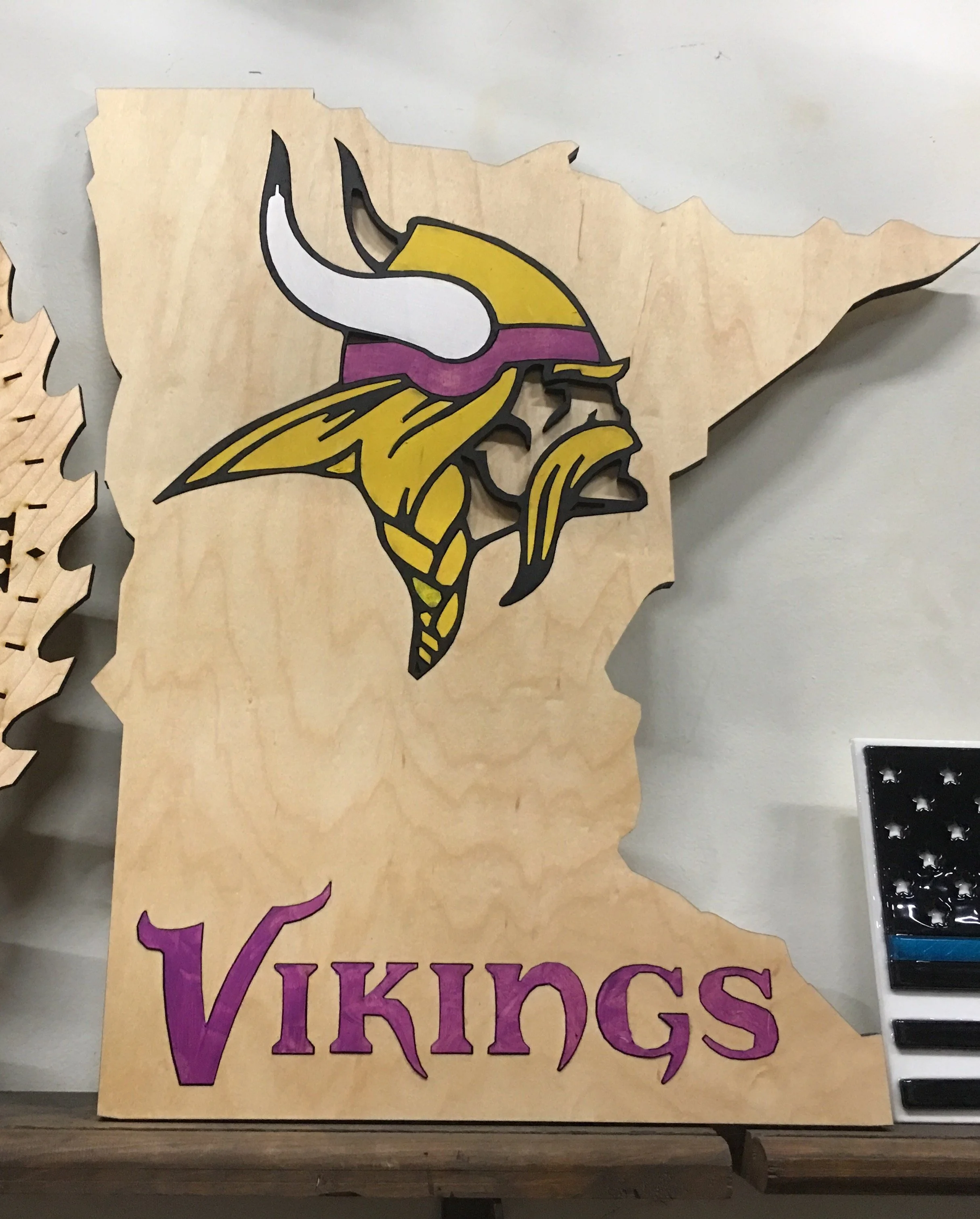 Wooden sign featuring the Minnesota Vikings logo and the word 'Vikings' painted in purple.