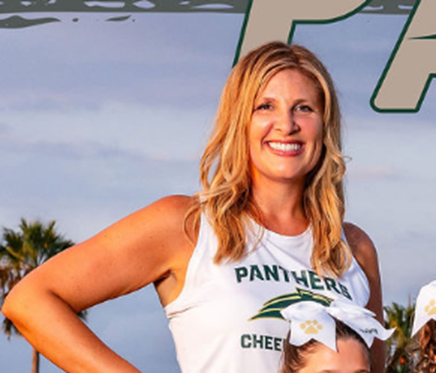Smiling woman in white cheerleading uniform with 'Panthers' text and paw print logo, standing outdoors with palm trees and cloudy sky in background.