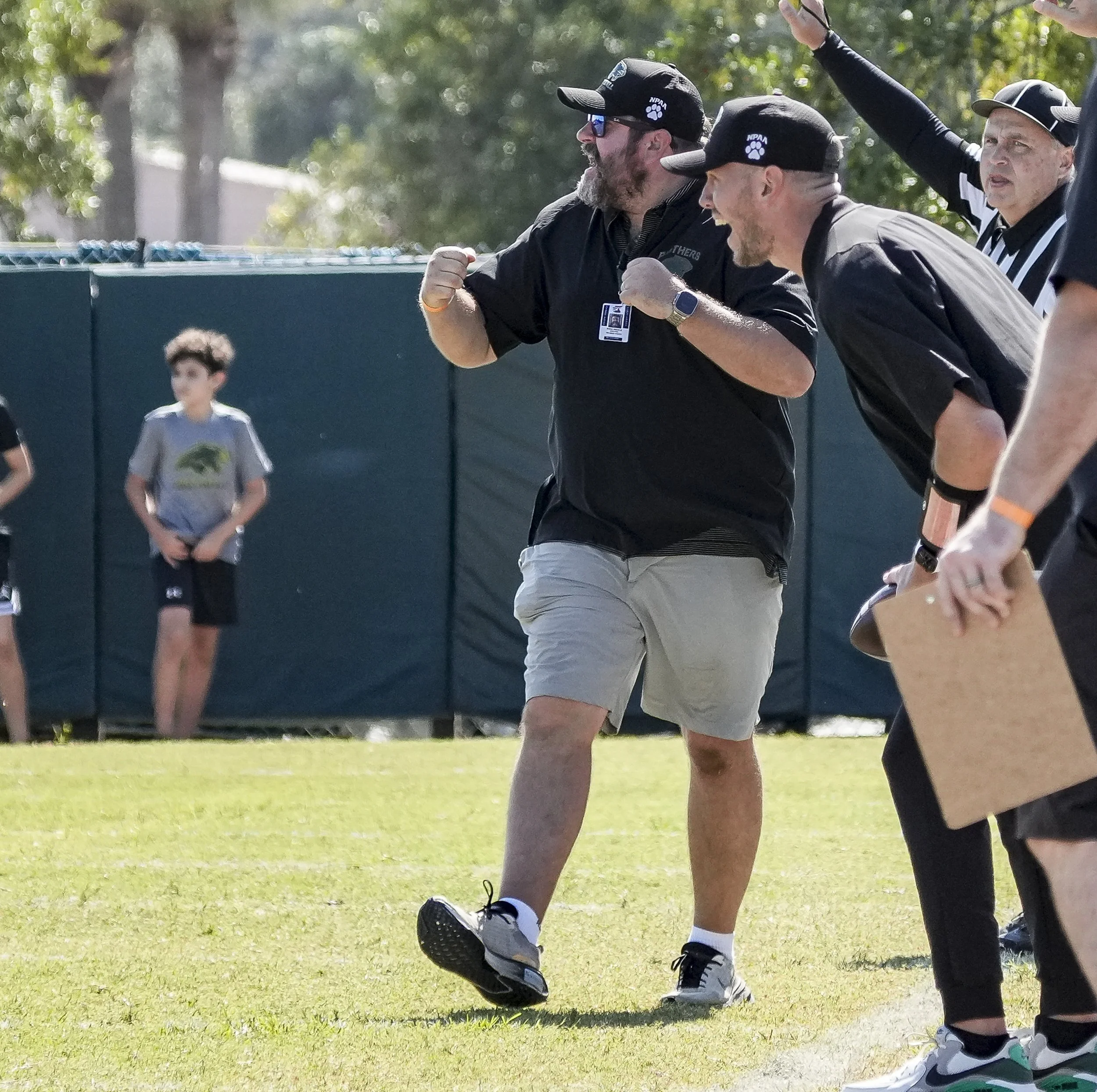 Fathers and children celebrating on a football field, with some adults raising their fists in celebration.