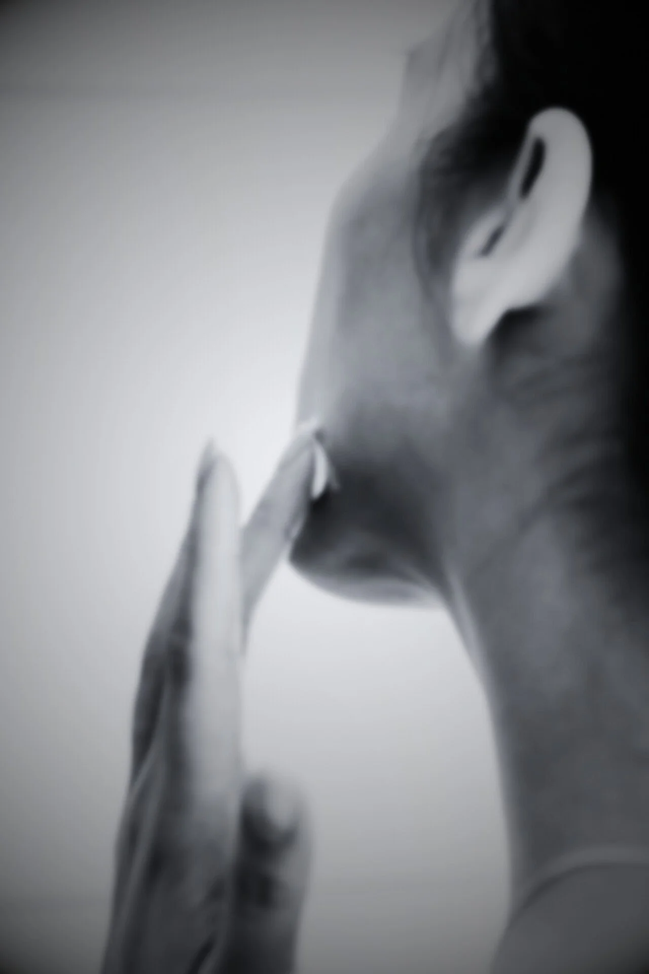 A black and white photo of a person applying face cream to their jawline.