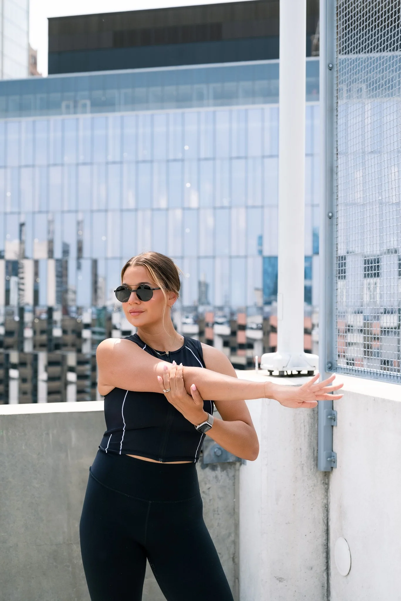 Woman stretching on rooftop with city buildings in background