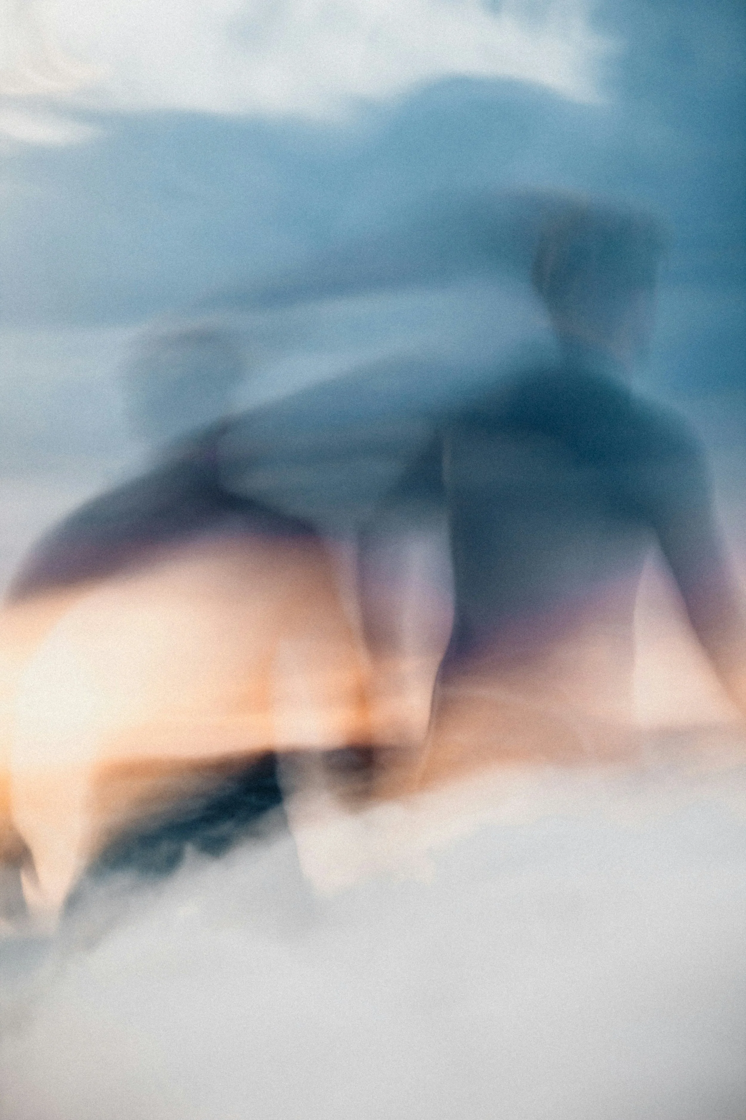A blurred abstract close-up of a person wearing a blue shirt, with indistinct facial features due to motion blur.
