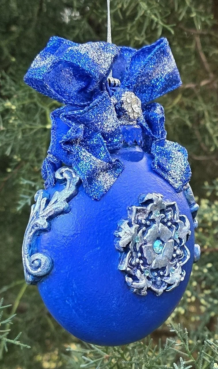 Side profile of the Celestial Blue Cross Ornament by Art Illusions by Young. The three-dimensional quality of the hand-sculpted and molded polymer clay is visible, with the ornate silver cross and delicate scrollwork rising from the rich cobalt blue 