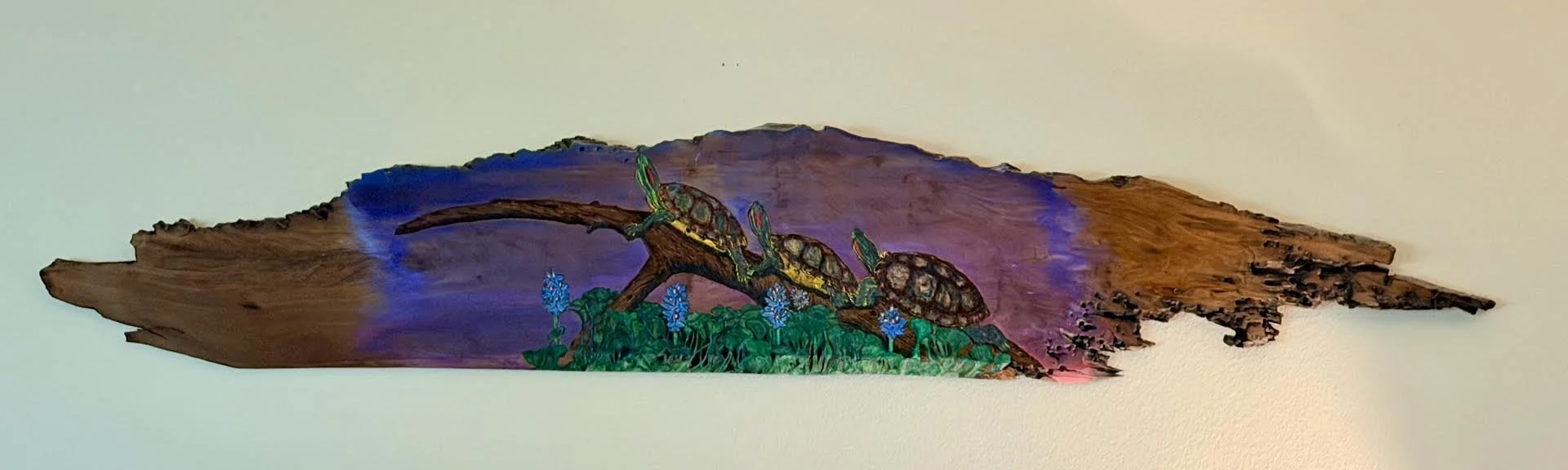 🟢 Available : 
Handcrafted woodburned and painted artwork by Art Illusions by Young from Folsom, Louisiana. Three red-eared slider turtles rest on a fallen log surrounded by blooming blue irises against a dramatic purple wetland backdrop. Created wi