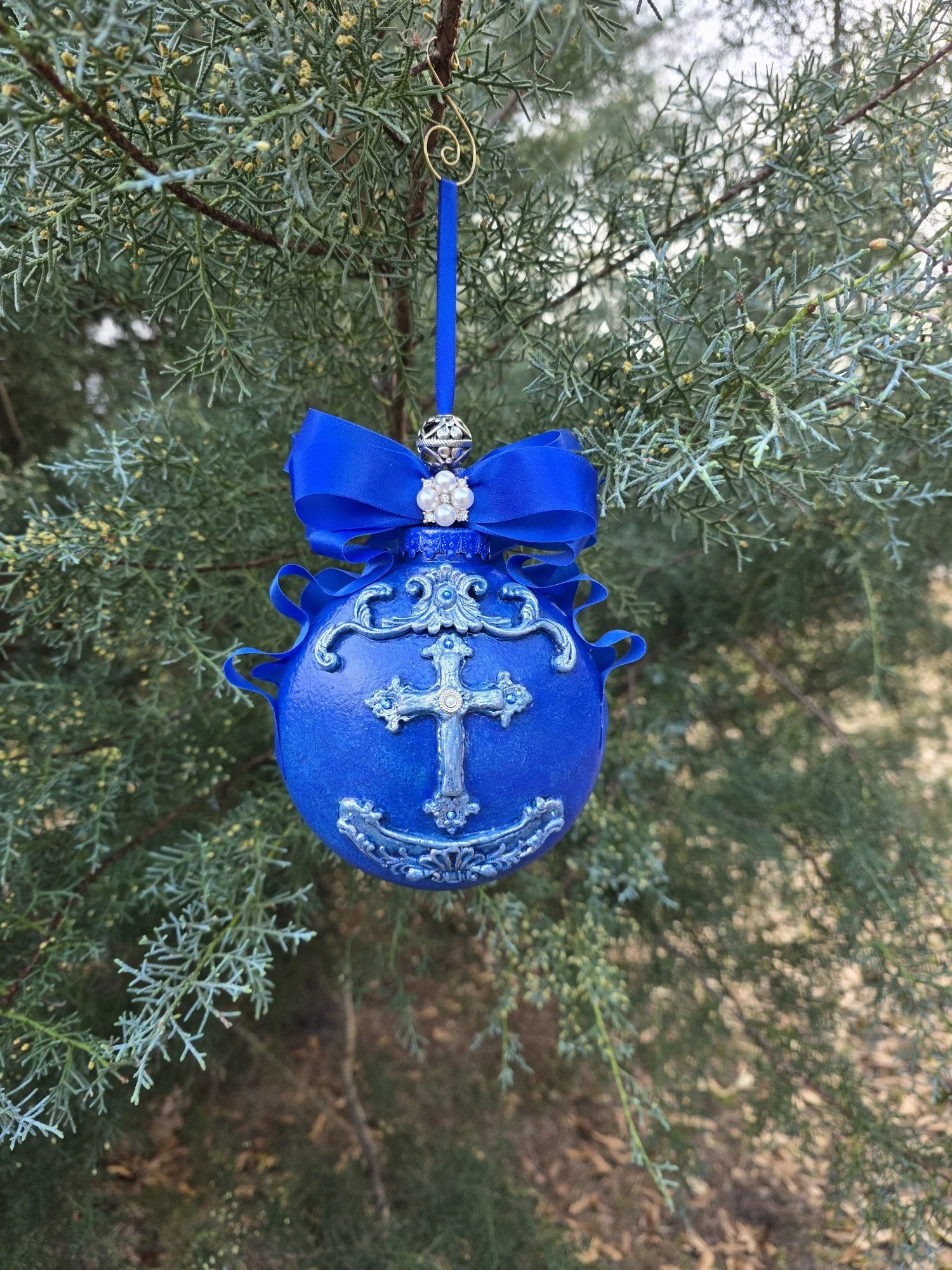 Front hanging view of the Royal Blue Cross Ornament by Art Illusions by Young. The ornate silver cross with delicate filigree and scrollwork stands in elegant contrast to the rich cobalt blue base with its subtle metallic sheen. A dramatic royal-blue