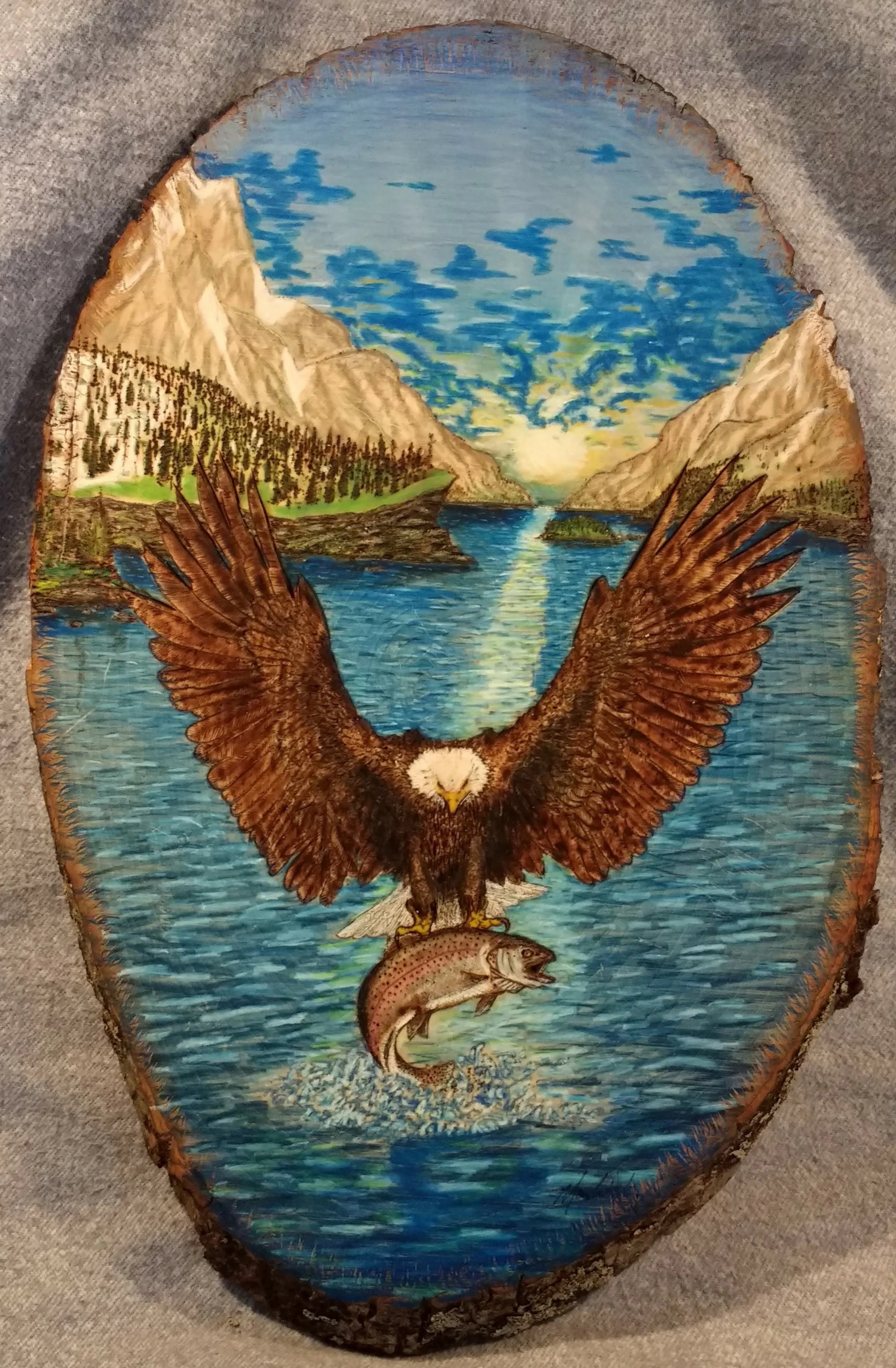 🔴 Sold: 
Eagle at Sunrise in Alaska Pyrography. Bald Eagle catching fish in the Alaska wilderness  artwork by Art Illusions by Young. Powerful moment of a bald eagle descending with talons extended toward a fish in blue water, framed in an oval wood