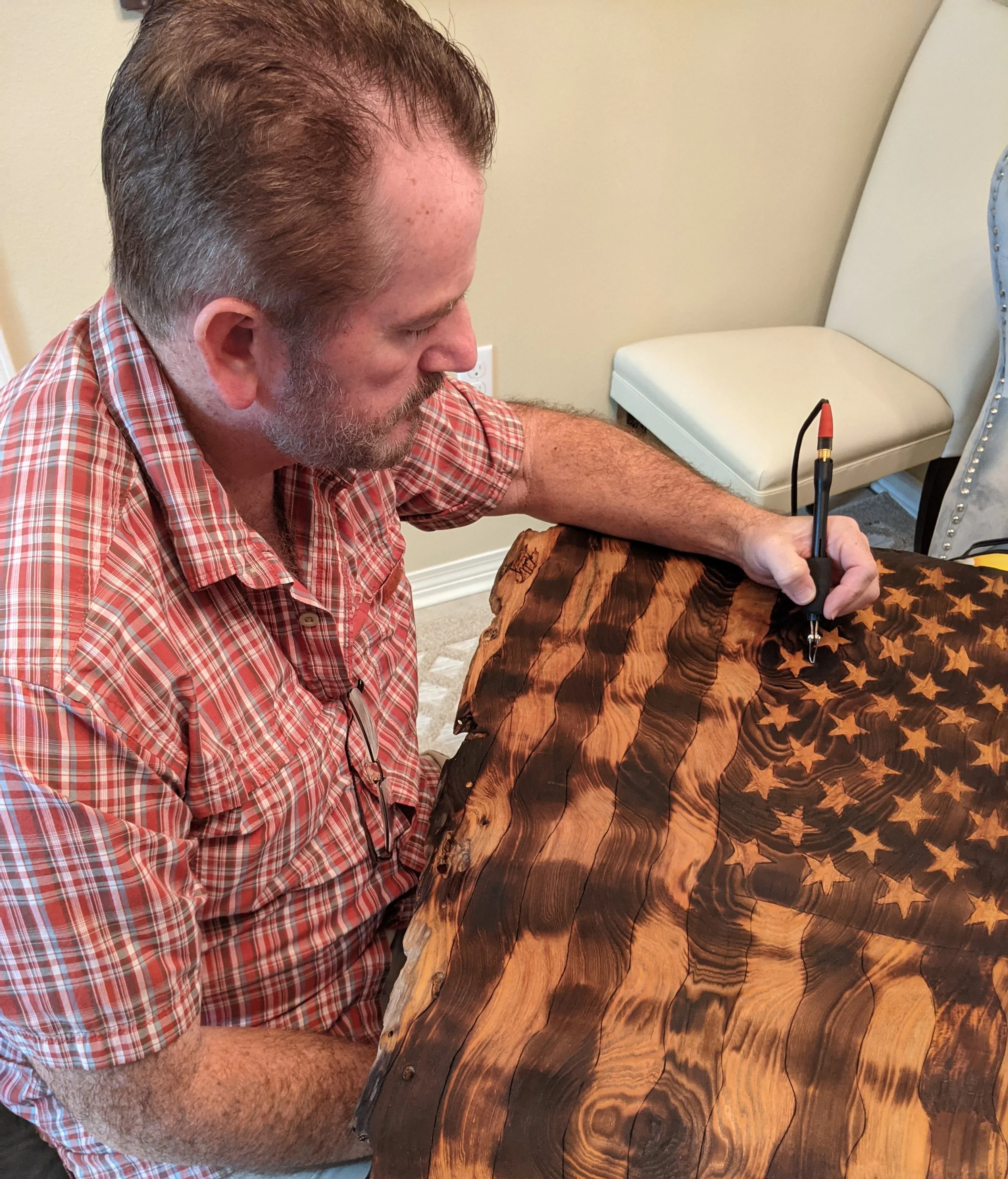 Mark Thomas Young of Art Illusions by Young using a pyrography tool to burn the American flag design into a wood slab for a Woodburn/Epoxy piece. Detailed handcrafted work in the Folsom, Louisiana studio.