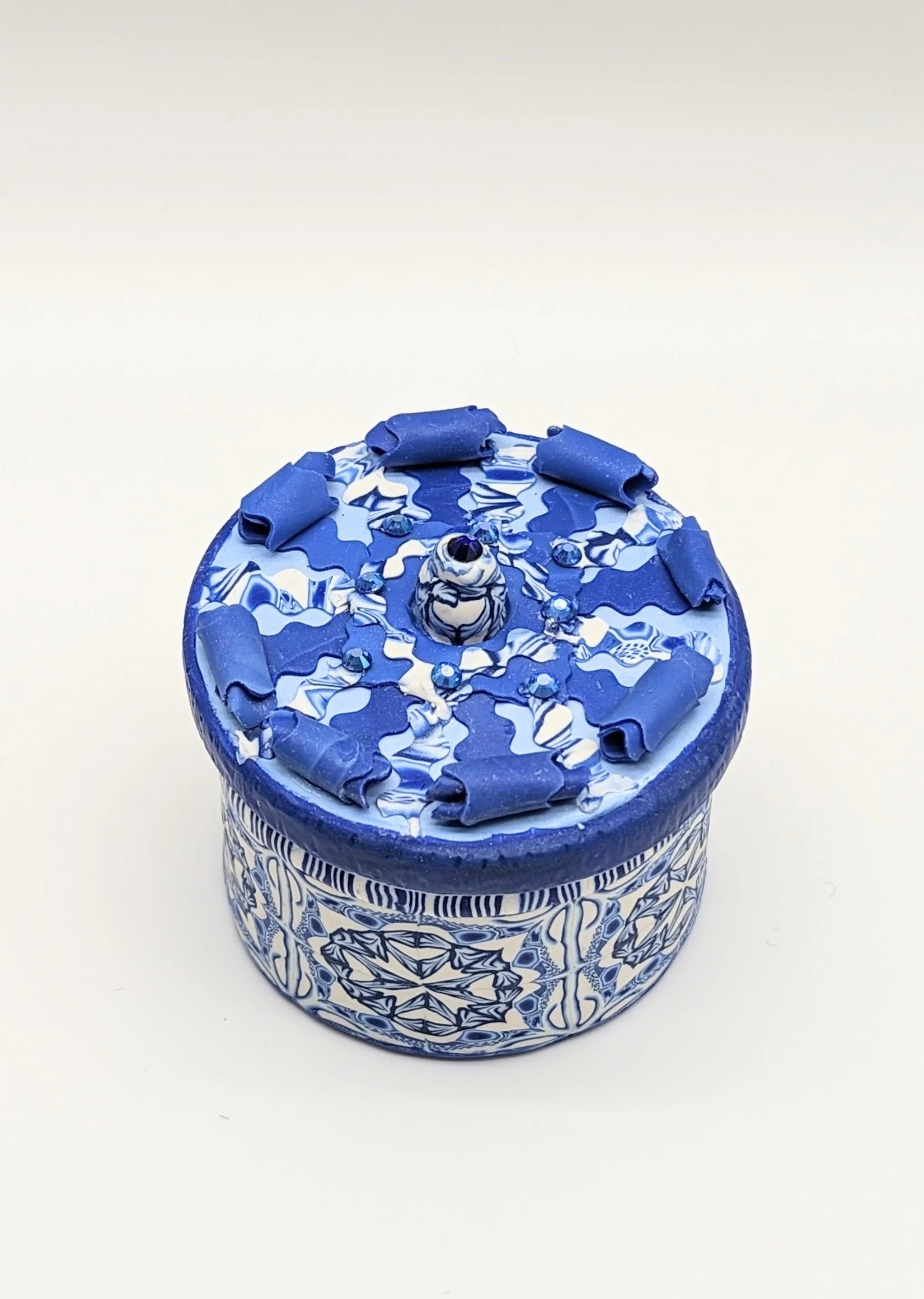 🔴 Sold: 
Blue Trinket Holder by Art Illusions by Young. A round trinket or jewelry holder covered in intricate blue and white polymer clay with floral and lace-like patterns. The detailed hand-sculpting creates a beautiful, functional decorative pie