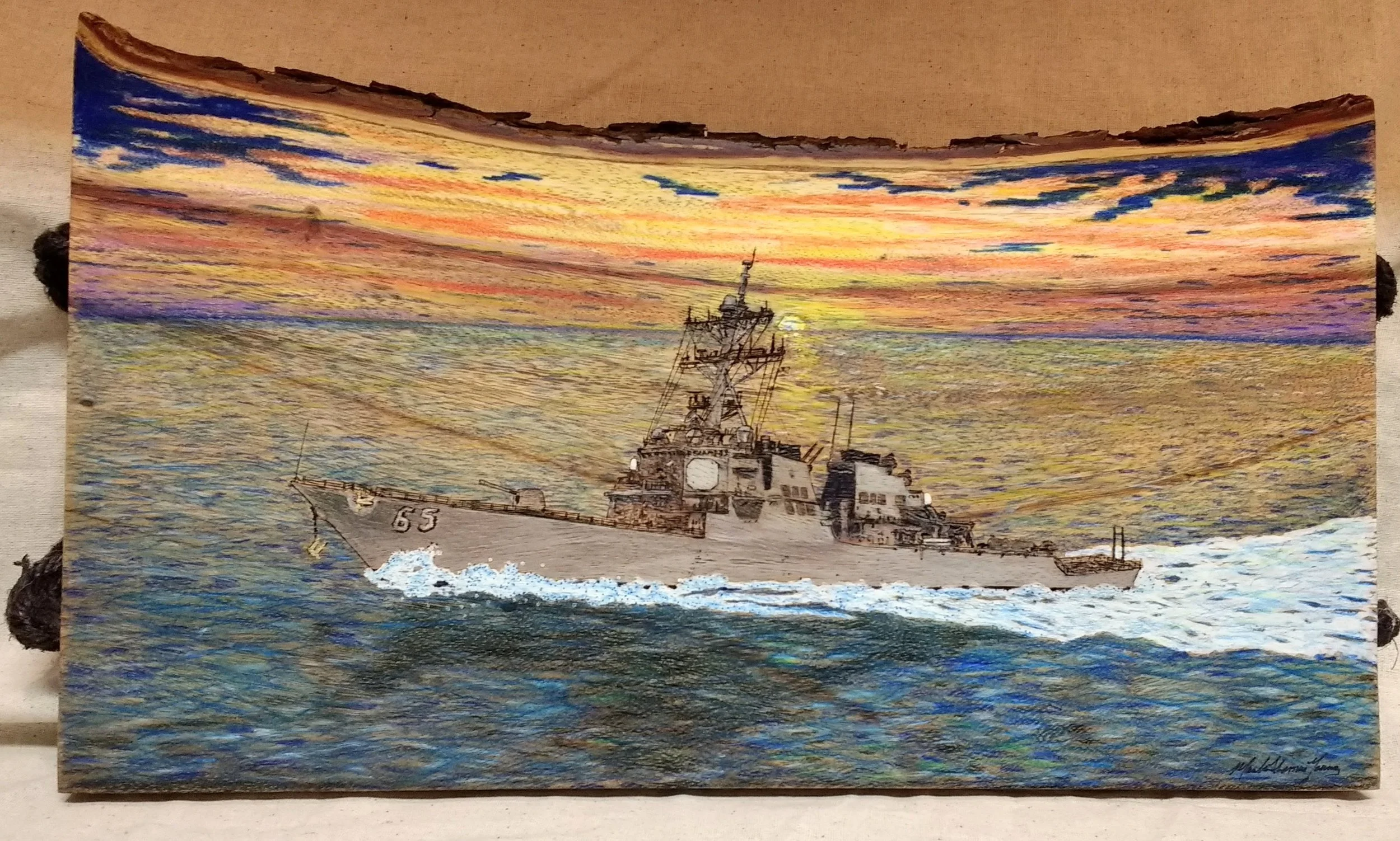 🔴 Sold:
Commission USS Benfold DDG-65 Sailing at Sunrise Pyrography by Art Illusions by Young, Folsom, Louisiana. This dramatic woodburn captures the Arleigh Burke-class destroyer USS Benfold sailing into a vibrant sunrise, its silhouette cutting th