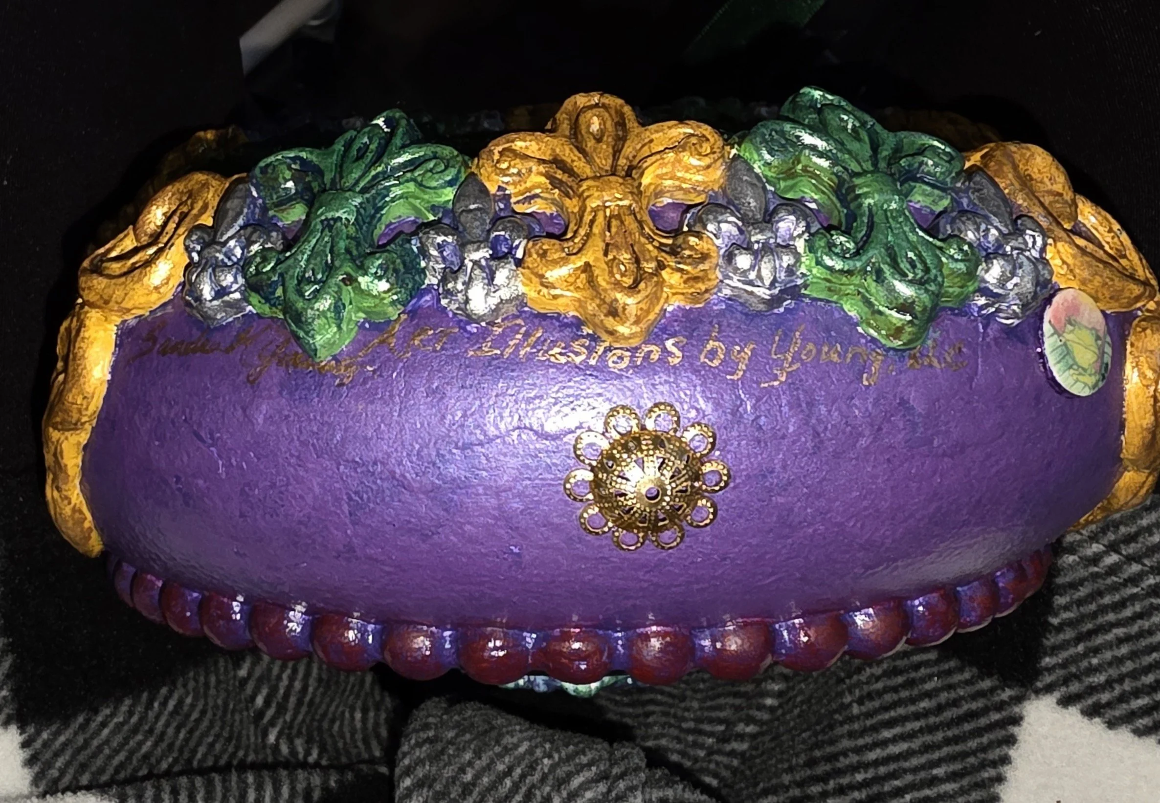 Dual Crown Royalty Ornament – Artist’s Signature View
This close-up reveals the underside of the Dual Crown Royalty Ornament, showcasing the rich purple base adorned with a delicate gold fleur-de-lis medallion and a luxurious border of deep red-purpl
