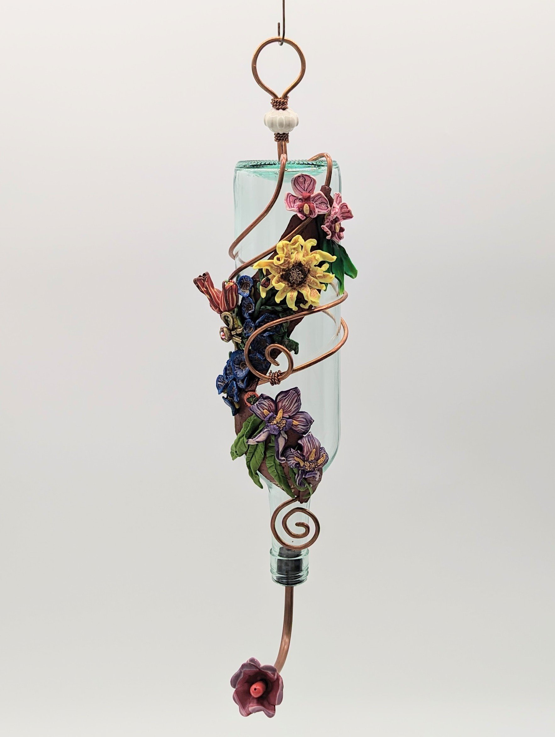 🔴 Sold: 
Handcrafted Hummingbird Feeder with Autumn Blooms by Art Illusions by Young, Folsom, Louisiana. This elegant feeder features a tall, slender recycled glass bottle gracefully wrapped in copper wire and adorned with hand-sculpted polymer clay