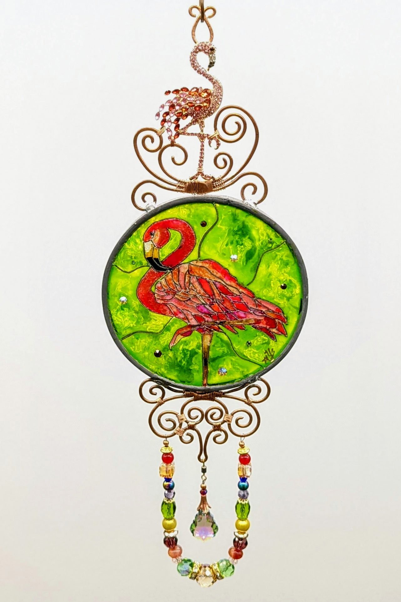 🔴 Sold: 
Flamingo Illusion Glass by Art Illusions by Young. A tall, graceful flamingo stands against a vibrant green background in this circular suncatcher. Rich pink tones and delicate details bring the iconic bird to luminous life.