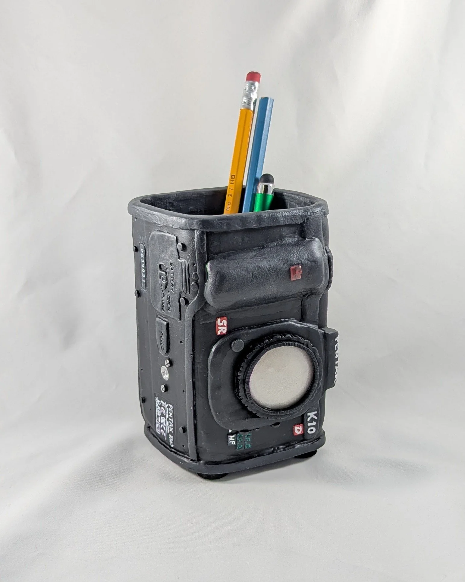 🔴 Sold: 
Camera Pencil / Soap Dispenser by Art Illusions by Young. This unique dispenser is crafted to resemble a vintage camera, covered in hand-sculpted black polymer clay with realistic details and metallic accents. A whimsical yet practical piec