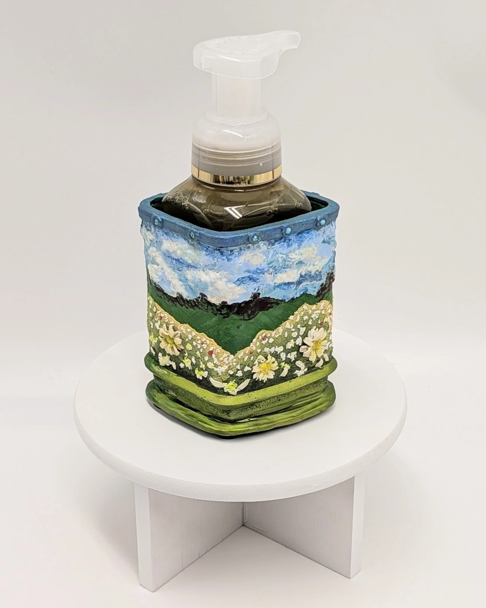 🔴 Sold: 
Spring Flowers in a Field Soap Dispenser by Art Illusions by Young. This cheerful dispenser features a hand-sculpted scene of spring wildflowers in a field, rendered in soft pastel polymer clay. The vibrant floral design brings fresh season