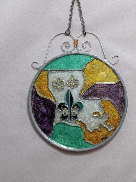 🔴 Sold: 
Louisiana Map Illusion Glass by Art Illusions by Young. This circular suncatcher beautifully renders the shape of Louisiana in rich gold, green, purple, and white tones with the iconic fleur-de-lis at its heart. A glowing celebration of Lou