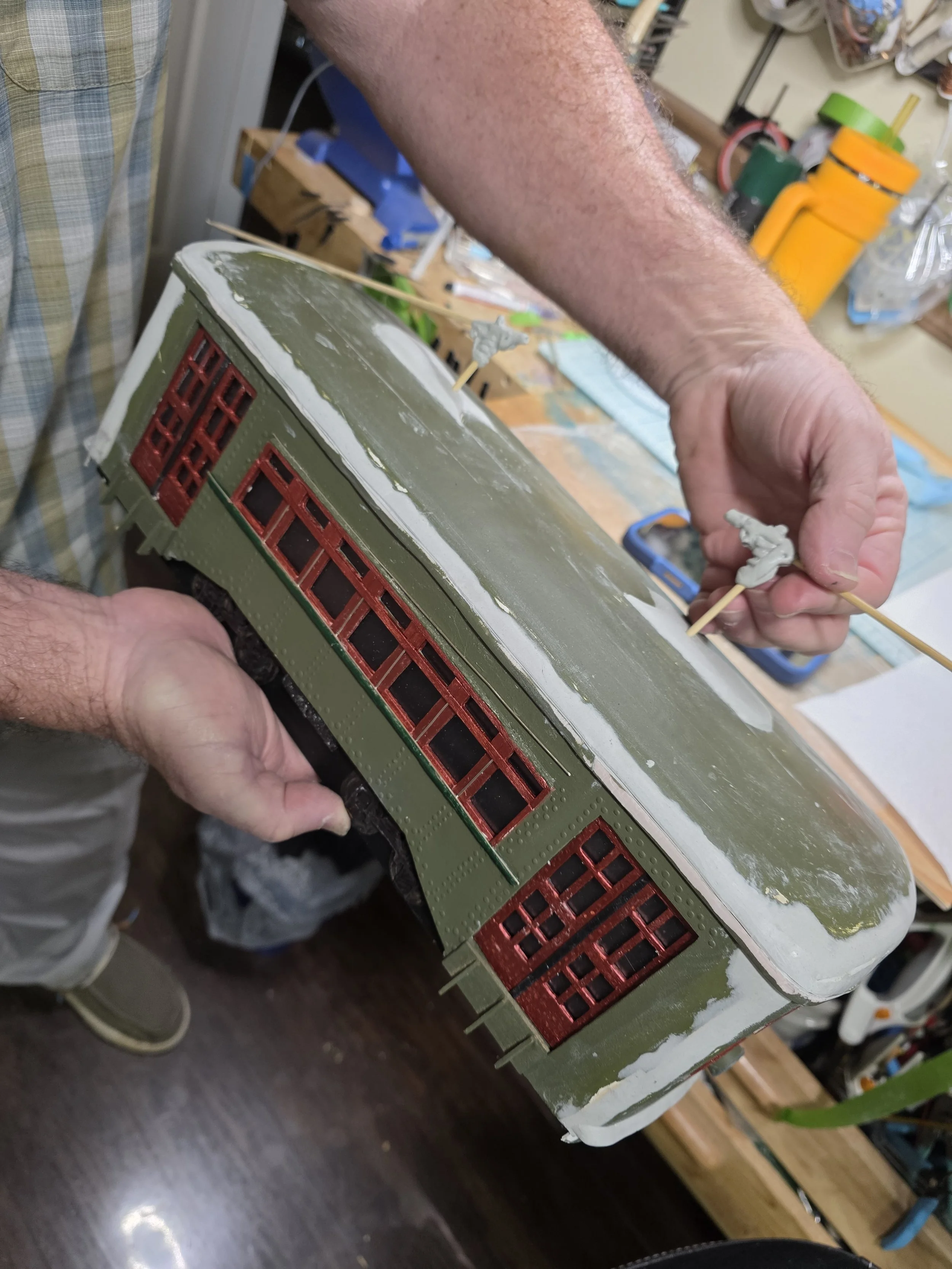 Behind-the-scenes view of the creation process: hands carefully painting and assembling the New Orleans streetcar tissue box cover diorama in the Art Illusions by Young studio in Folsom, Louisiana.