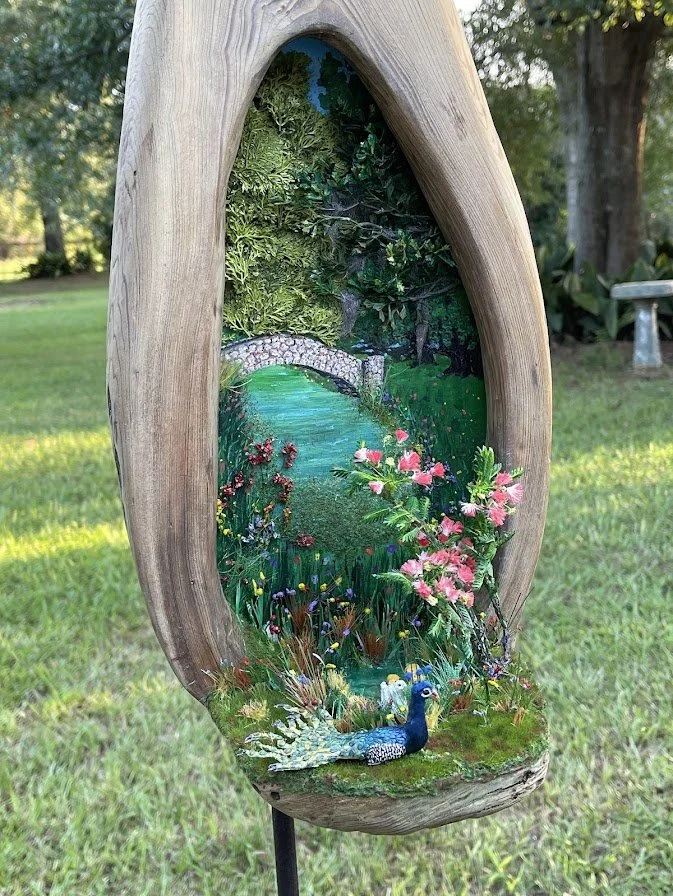 Angled perspective of the Enchanted City Park Serenity diorama highlighting the natural hollow in the cypress trunk, peacock, miniature pond, bridge, and blooming flowers. Museum-quality mixed media artwork by Art Illusions by Young.
