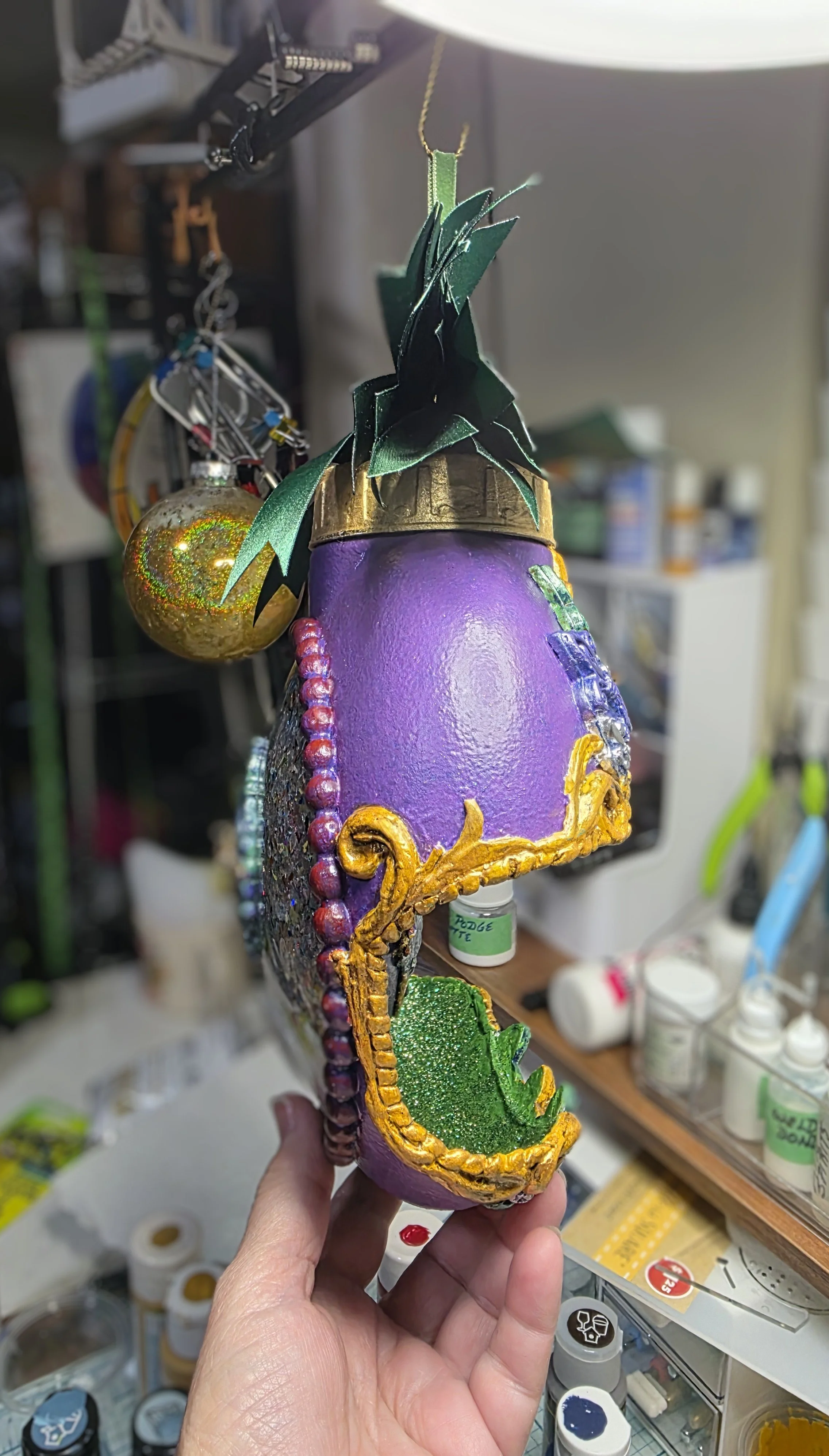 The Dual Crown Royalty Ornament in progressive build stages, held by the artist, with side view, demonstrating its impressive size and craftsmanship. Measuring approximately 10” × 8” (including bow and hanger), this one-of-a-kind piece combines molde