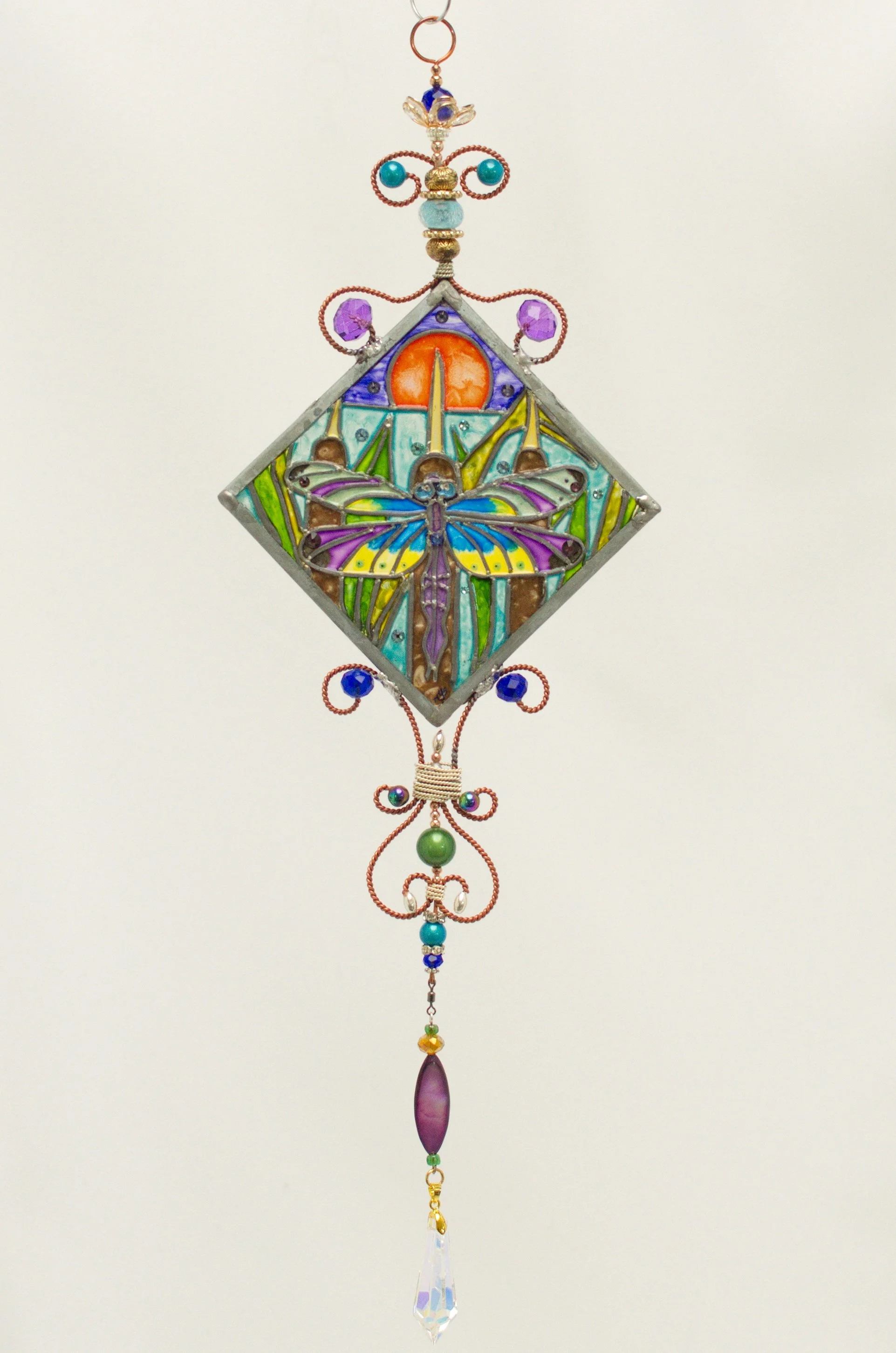 🔴 Sold: 
Dragonfly at Sunset Illusion Glass by Art Illusions by Young. A graceful dragonfly hovers above water in this round suncatcher, its iridescent wings catching the warm hues of a setting sun. European glass paints produce luminous color shift