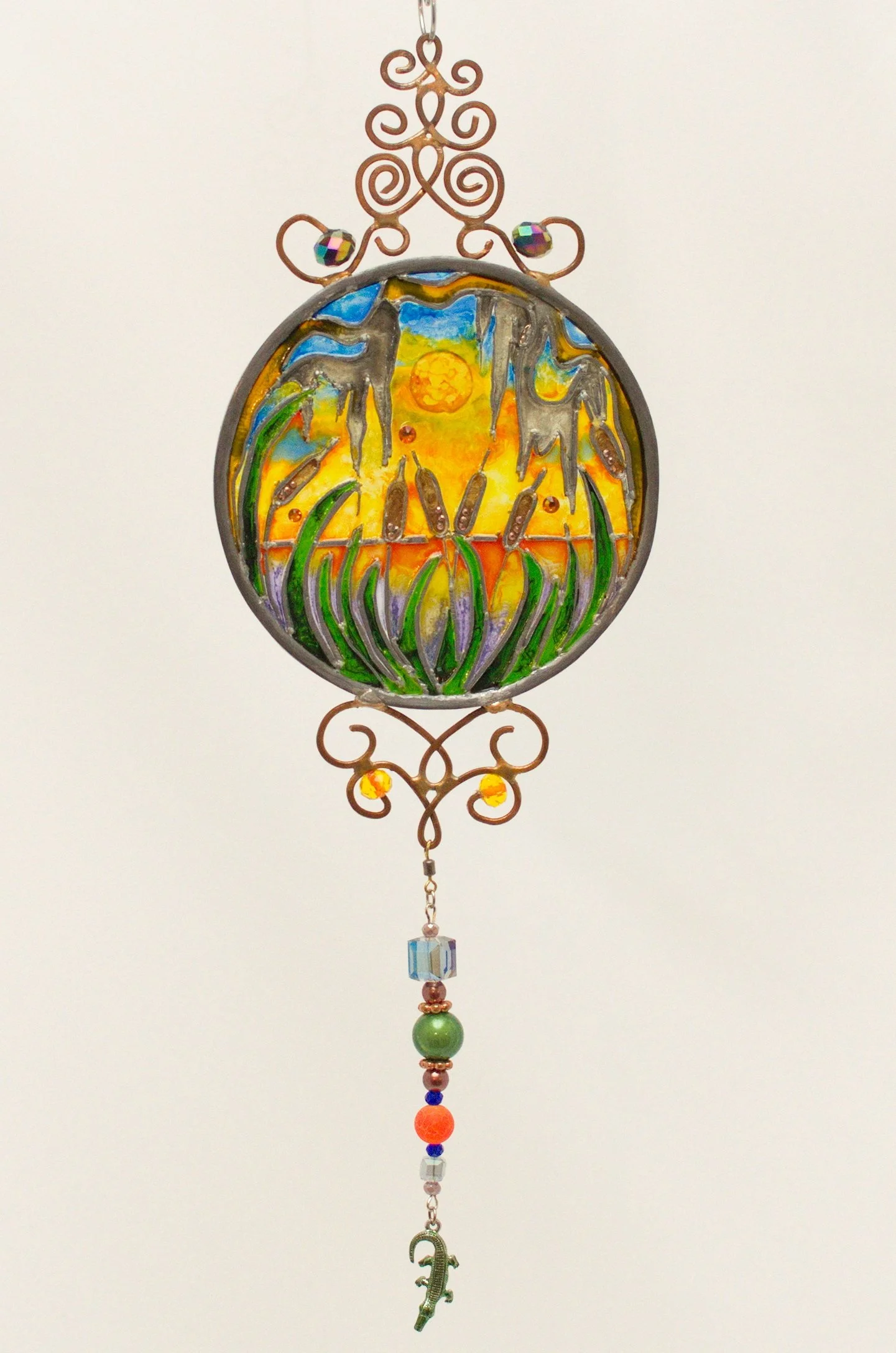 🔴 Sold: 
Cattails at Sunset Illusion Glass by Art Illusions by Young. Tall cattails stand silhouetted against a dramatic sunset in this serene round suncatcher. Warm oranges, purples, and deep blues in hand-painted glass create a peaceful Louisiana 