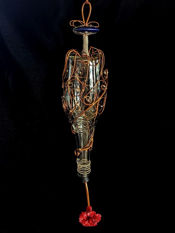 Frontal view on black background of the Copper Spiral Grace Hummingbird Feeder by Art Illusions by Young. The clear glass bottle features graceful copper wire spirals and a singular hand-sculpted polymer clay accent, creating a harmonious blend of re