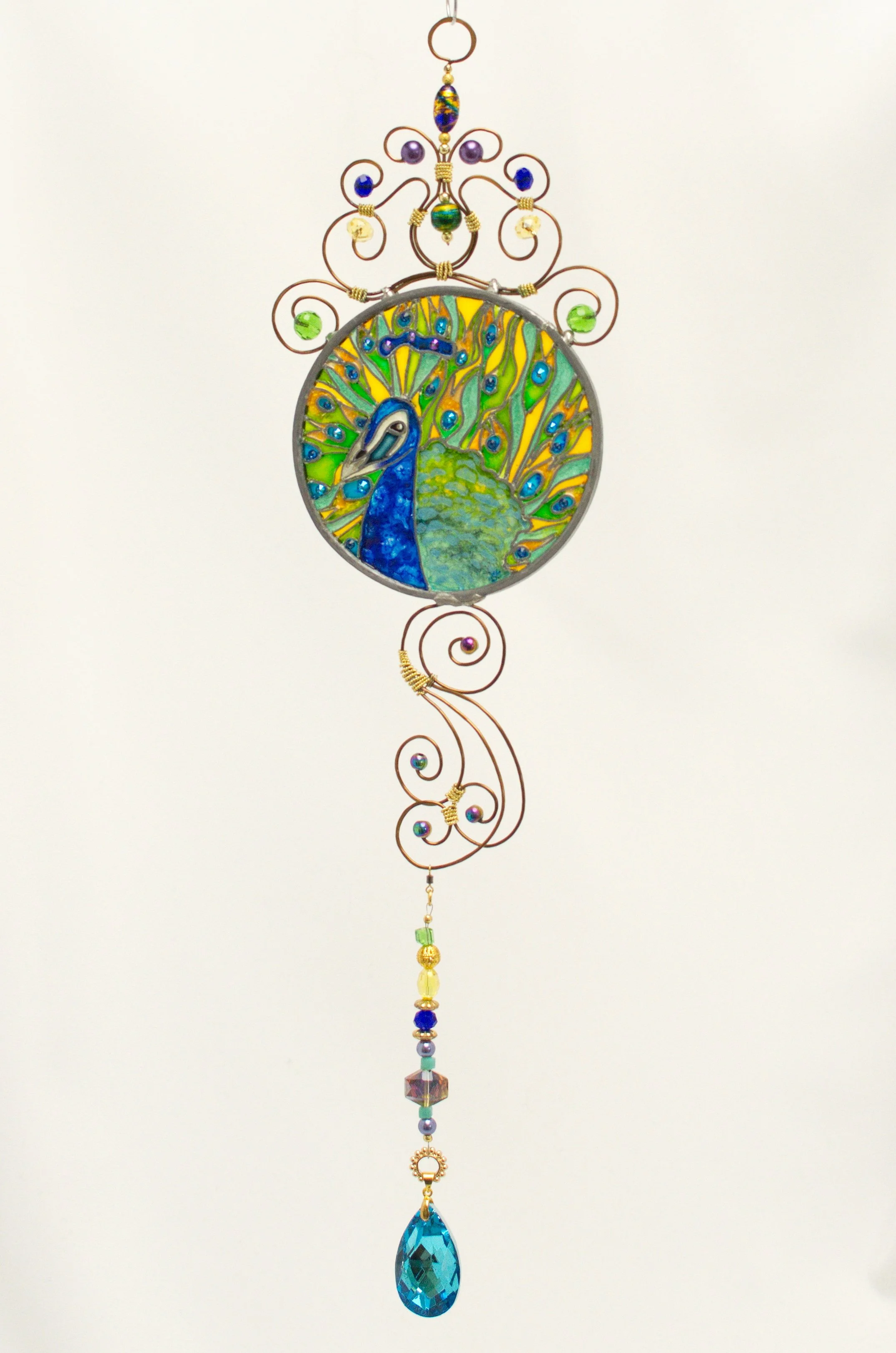 🔴 Sold: 
Peacock Illusion Glass by Art Illusions by Young, Folsom, Louisiana. This elegant circular suncatcher features a majestic peacock displaying its iridescent tail feathers against a lush green background. Hand-painted with European glass pain
