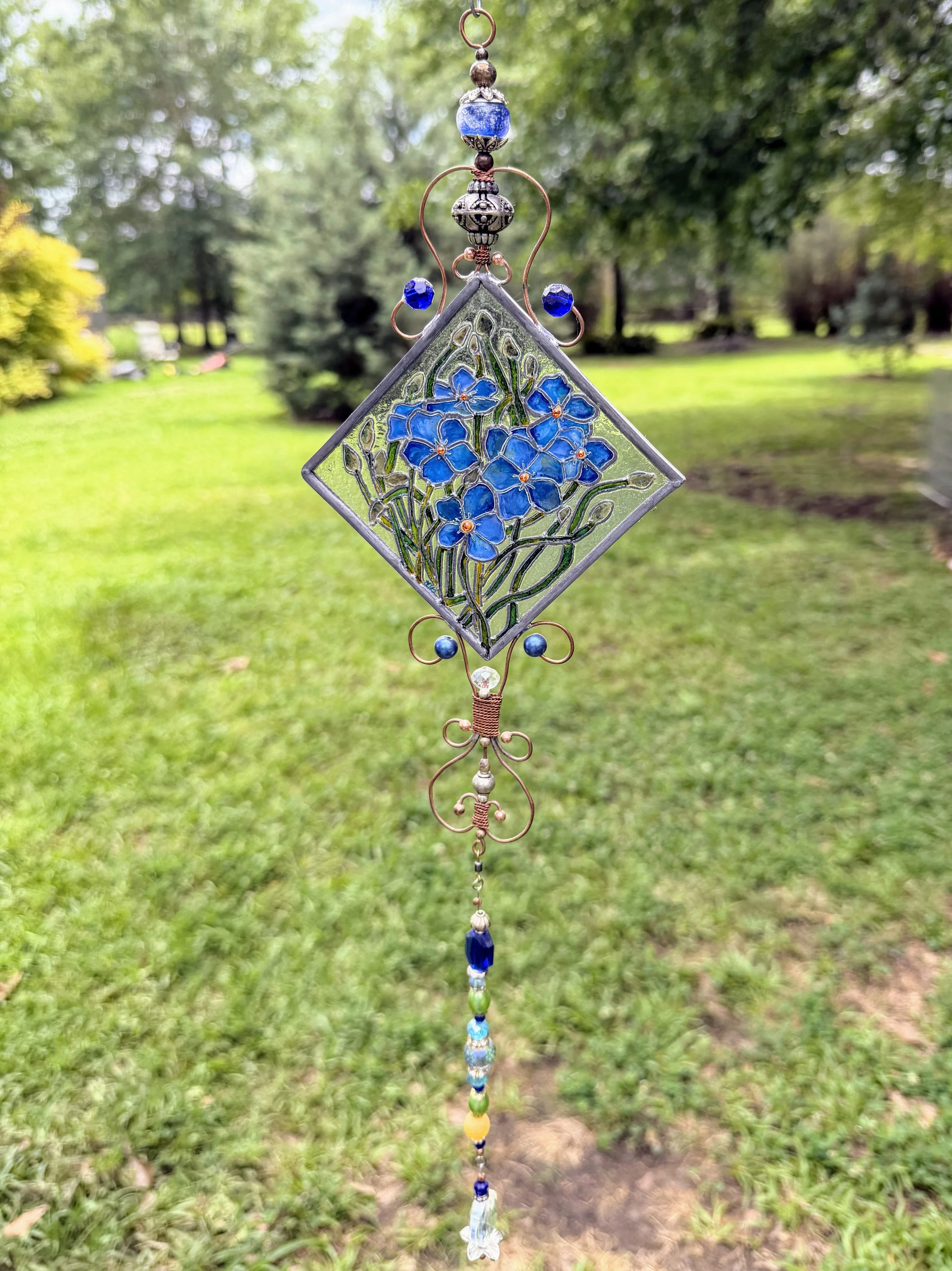 Forget-Me-Nots by Art Illusions by Young. A delicate cluster of vibrant blue forget-me-not flowers blooms eternally in this hand-painted and leaded Illusion Glass panel. Soft blue petals with golden centers and gentle green foliage are rendered with 