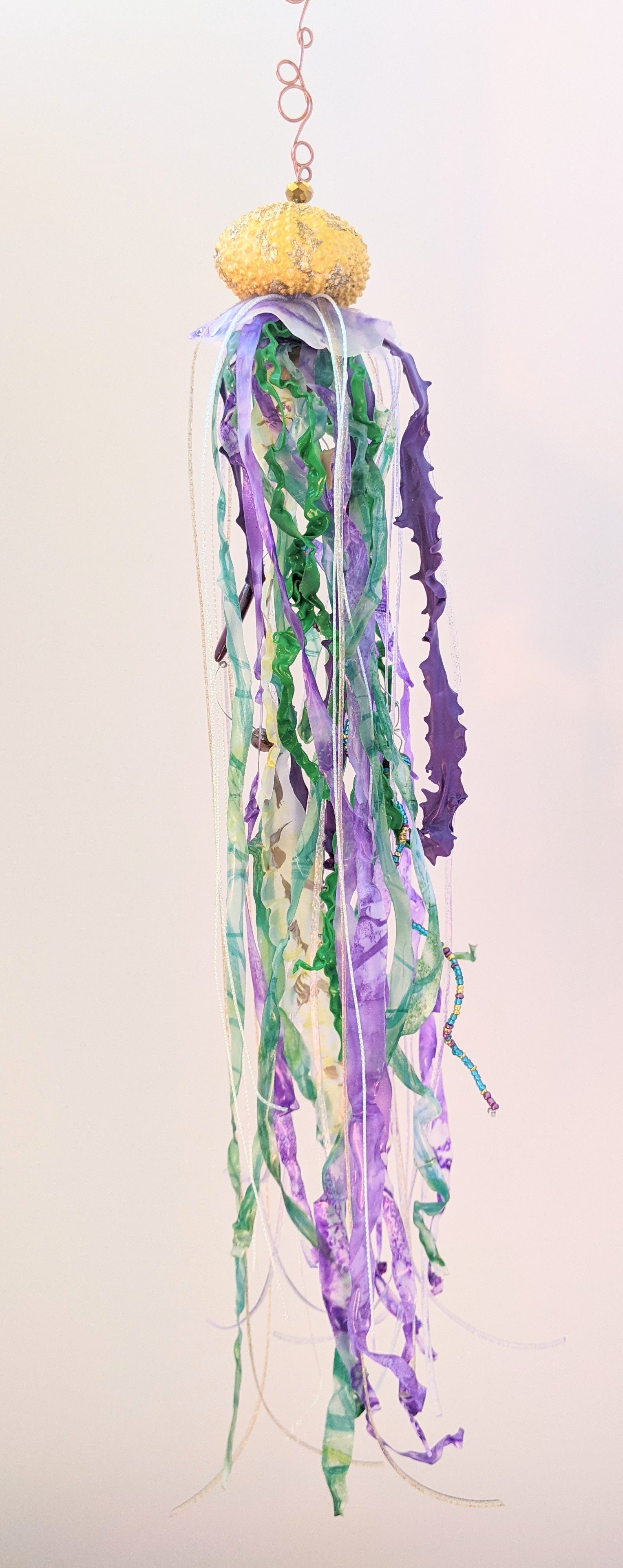 🟢 Available :
Jellyfish Suncatcher – Purple & Green Drift by Art Illusions by Young from Folsom, Louisiana. This luminous jellyfish suncatcher captures the ethereal beauty of ocean life in motion. Handcrafted with a genuine sea urchin bell and artis