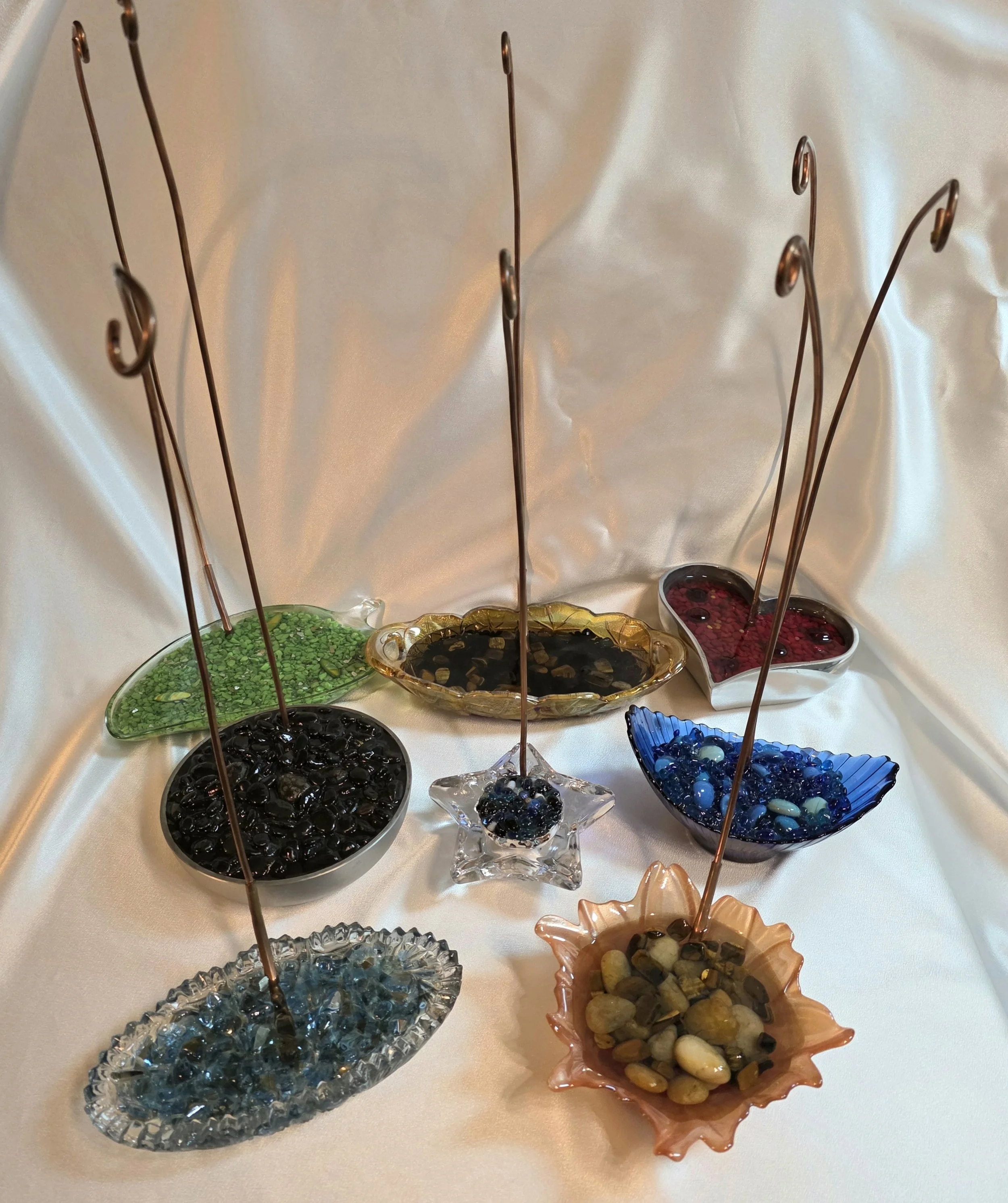 Selection of handcrafted display stands by Art Illusions by Young.
Each stand features a unique vintage or antique base (pewter, leaded glass, blown glass, and more) paired with a solid copper rod. The bases are artistically layered with epoxy, crush