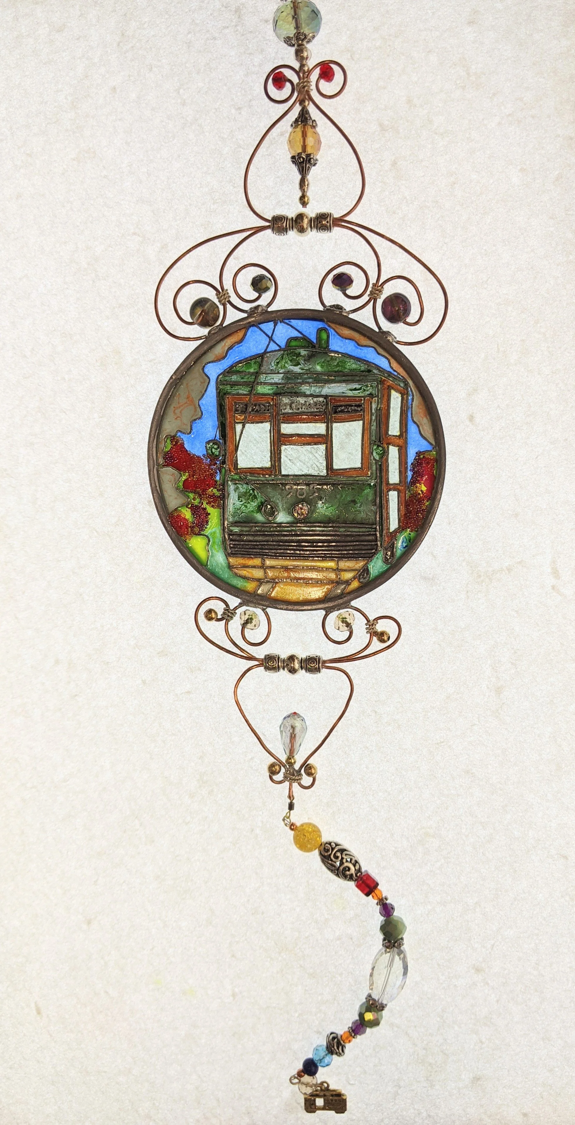 🔴 Sold: 
New Orleans Streetcar Illusion Glass by Art Illusions by Young. The beloved green St. Charles Avenue streetcar glides past live oaks in this luminous circular suncatcher. Hand-painted details capture the romance and history of New Orleans t