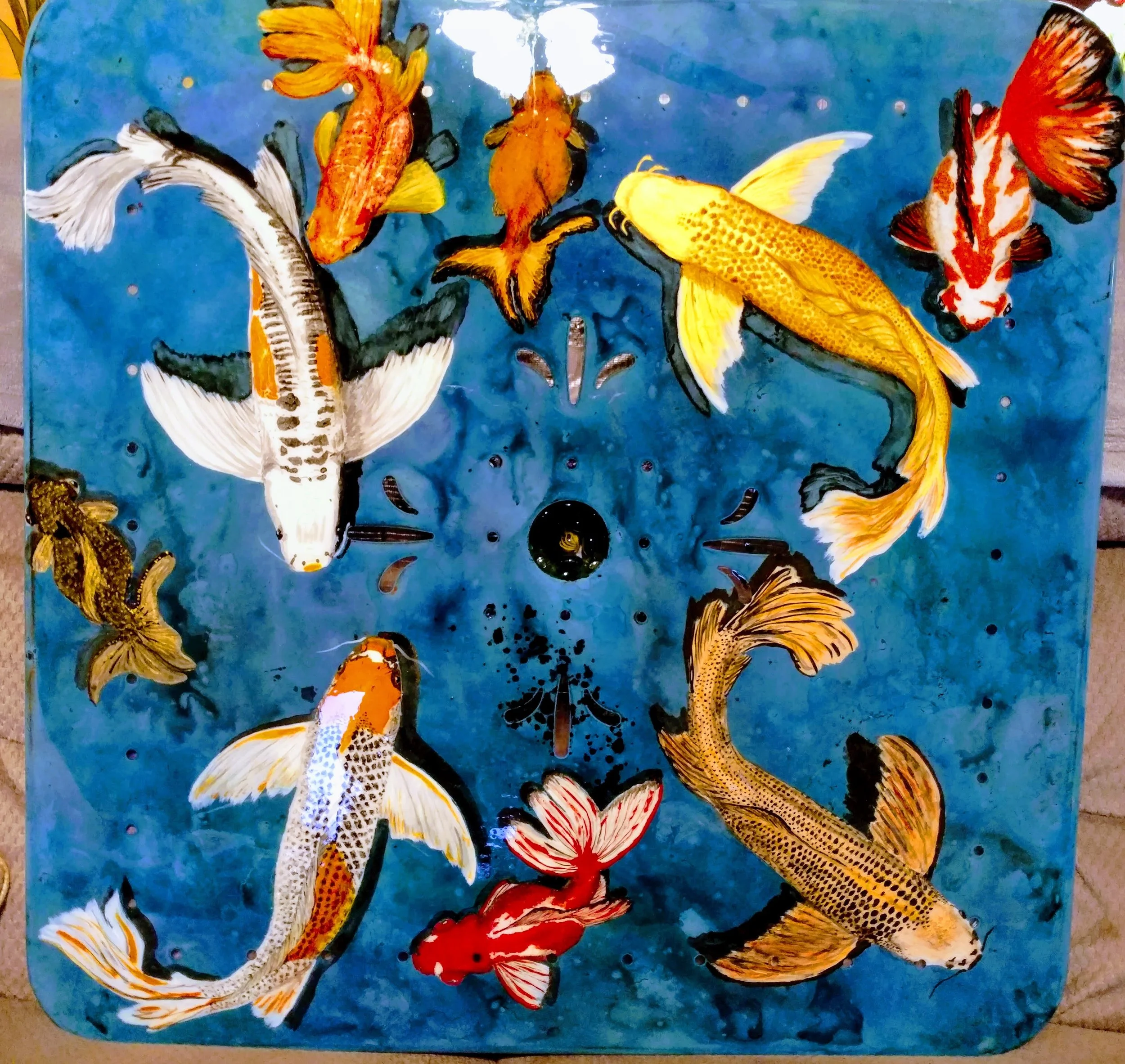 🟢 Available :
Vibrant hand-painted koi fish scene by Art Illusions by Young. Multiple colorful fantail and butterfly koi swim in a deep blue pond on a square metal surface. This dynamic original design is created with multiple metallic-enhanced brig
