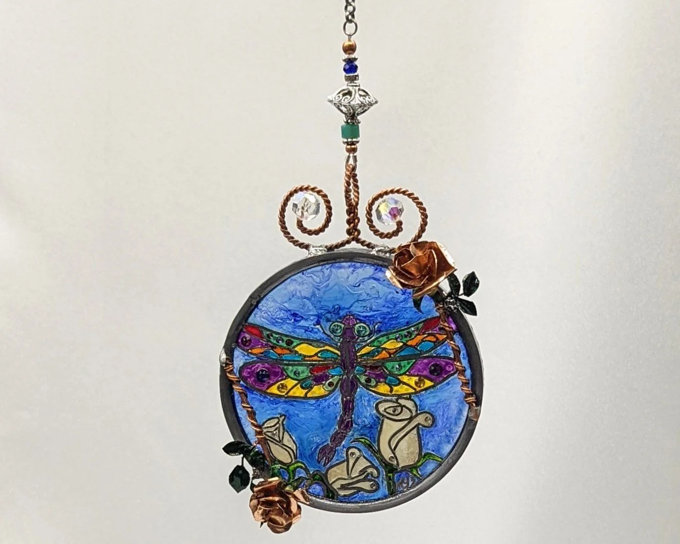 🔴 Sold: 
Commission Dragonfly with Rose Gold Illusion Glass by Art Illusions by Young. This delicate round suncatcher shows a shimmering dragonfly hovering near a soft pink rose. Sparkling bead accents and European glass paints create an ethereal, l