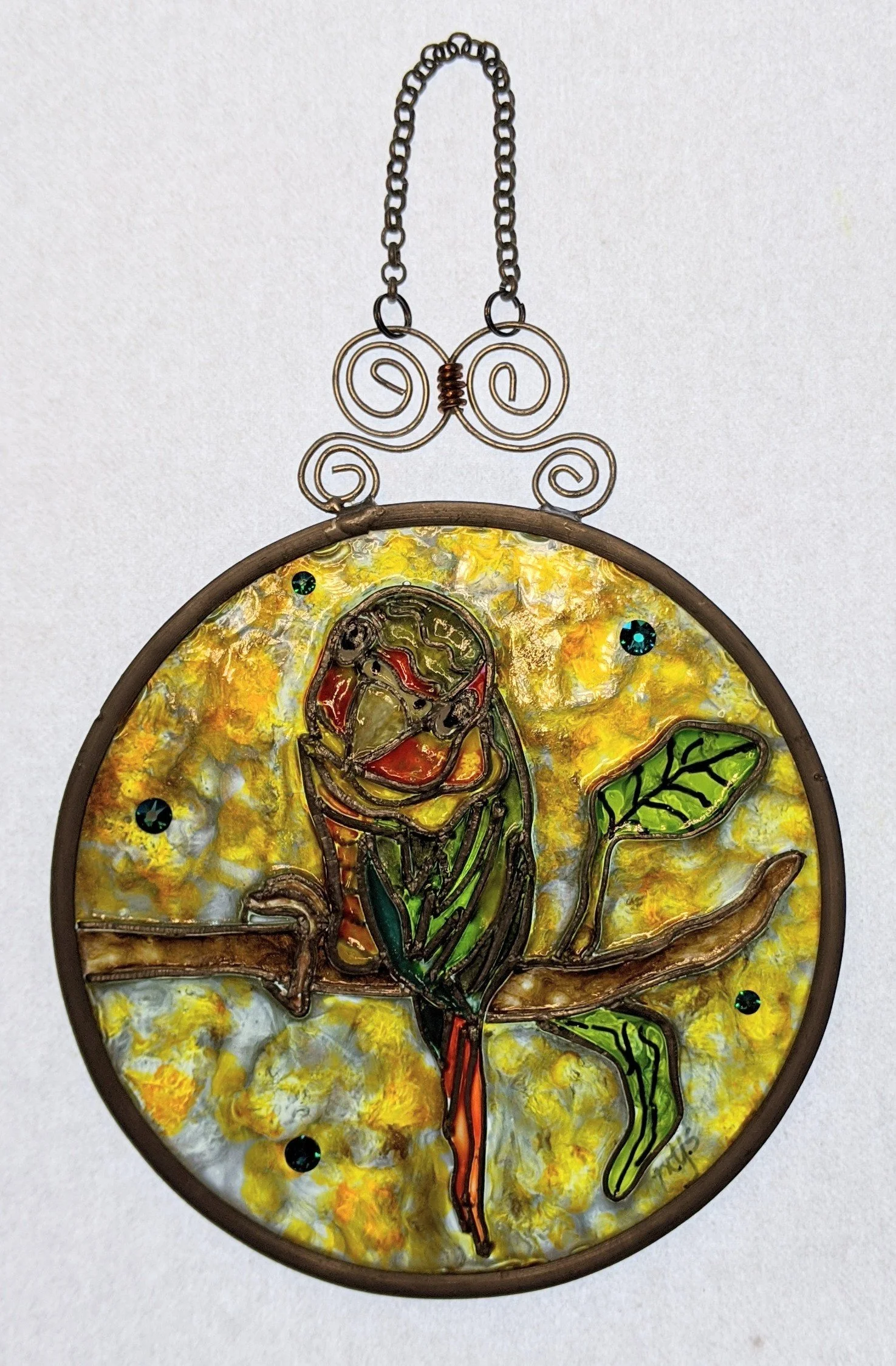 🔴 Sold: 
Sun Conure Parrot Illusion Glass by Art Illusions by Young. A vibrant round suncatcher featuring a colorful Sun Conure parrot perched on a branch, its bright orange, yellow, and green plumage glowing against a lush background. The lively pa