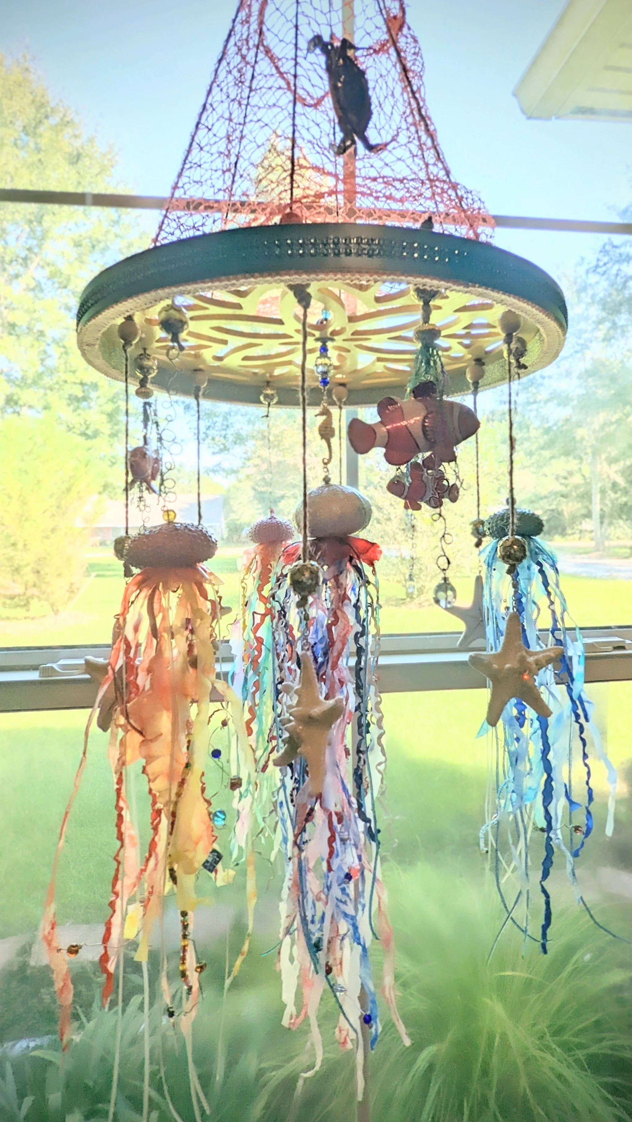 Full hanging view of the Nautical Jellyfish Mobile – Ocean Wonder for the Nursery by Art Illusions by Young. Measuring approximately 1.5 feet wide by 3 feet long, this impressive mobile features a netted canopy with four miniature Chihuly-inspired se