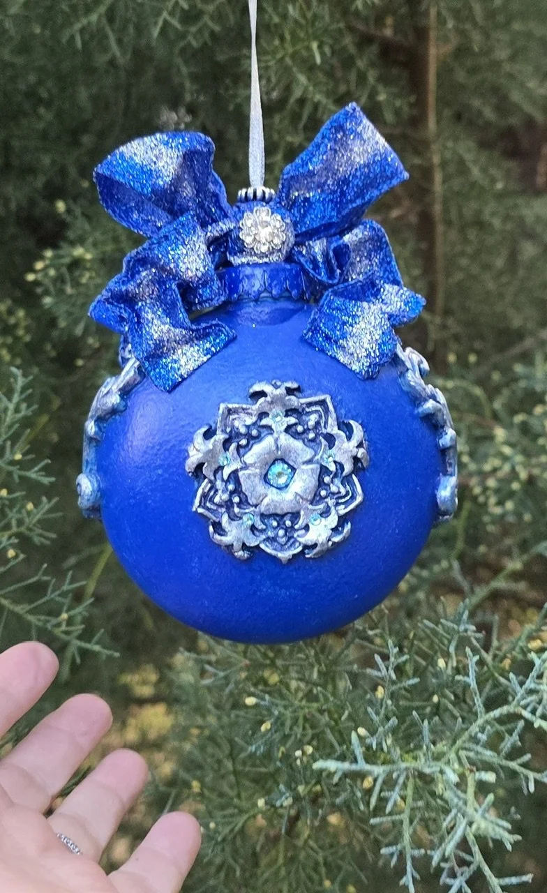 Rear view of the Celestial Blue Cross Ornament by Art Illusions by Young. The ornate silver medallion with delicate filigree and scrollwork stands in elegant contrast to the deep cobalt blue base with its subtle metallic sheen. Intricate raised flour