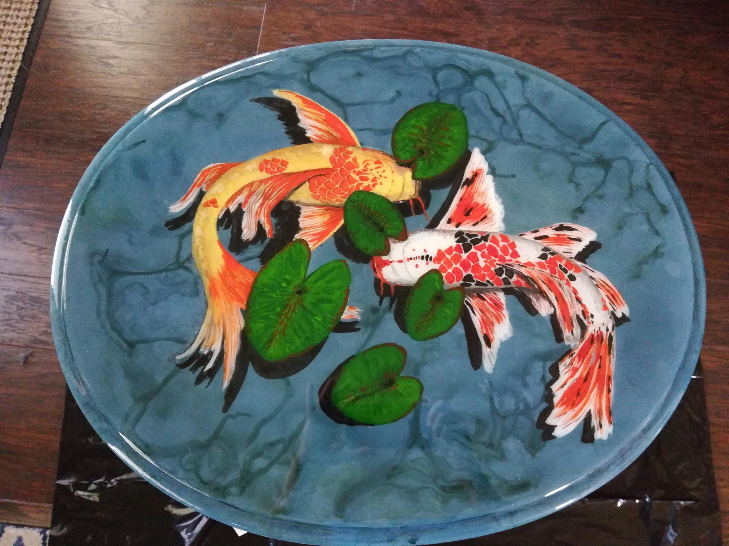 🔴 Sold:
Butterfly Koi Pond Epoxy Table by Art Illusions by Young, Folsom, Louisiana. This stunning epoxy river table features two vibrant butterfly koi gliding gracefully among floating lily pads on a deep blue pond surface. The hand-painted koi dis