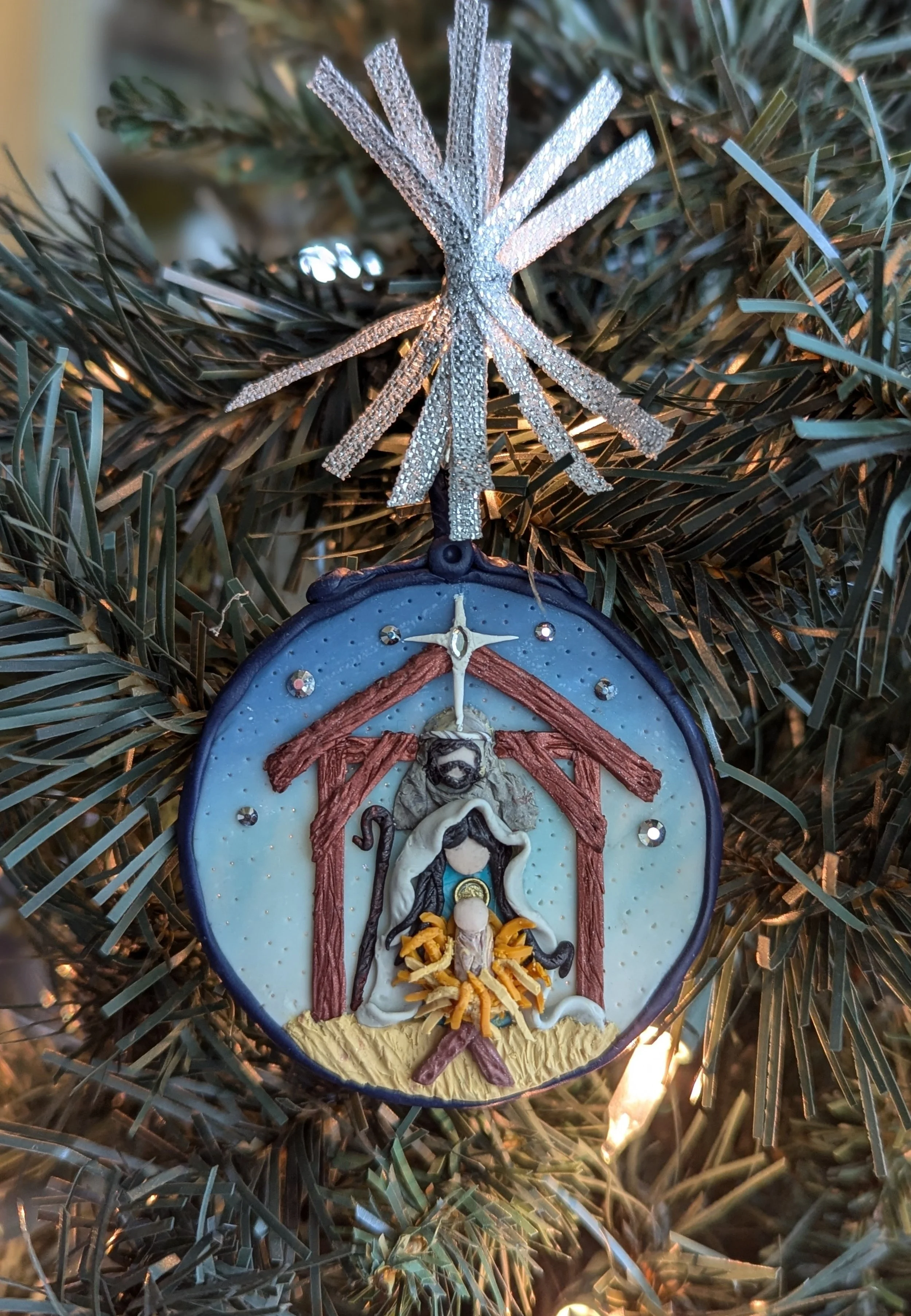 Nativity Manger Ornament by Art Illusions by Young from Folsom, Louisiana. This hand-sculpted manger scene tenderly portrays the sacred moment of Christmas — the birth of the Christ Child in a humble stable. Mary, Joseph, and the infant Jesus rest in