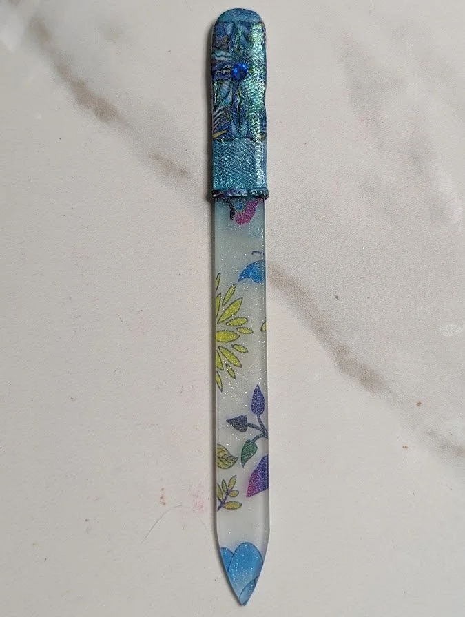 🔴 Sold: 
Polymer Clay Decorated Glass Fingernail File by Art Illusions by Young, Folsom, Louisiana. This elegant and functional fingernail file features a glass base completely transformed with intricate hand-sculpted polymer clay in shimmering shad