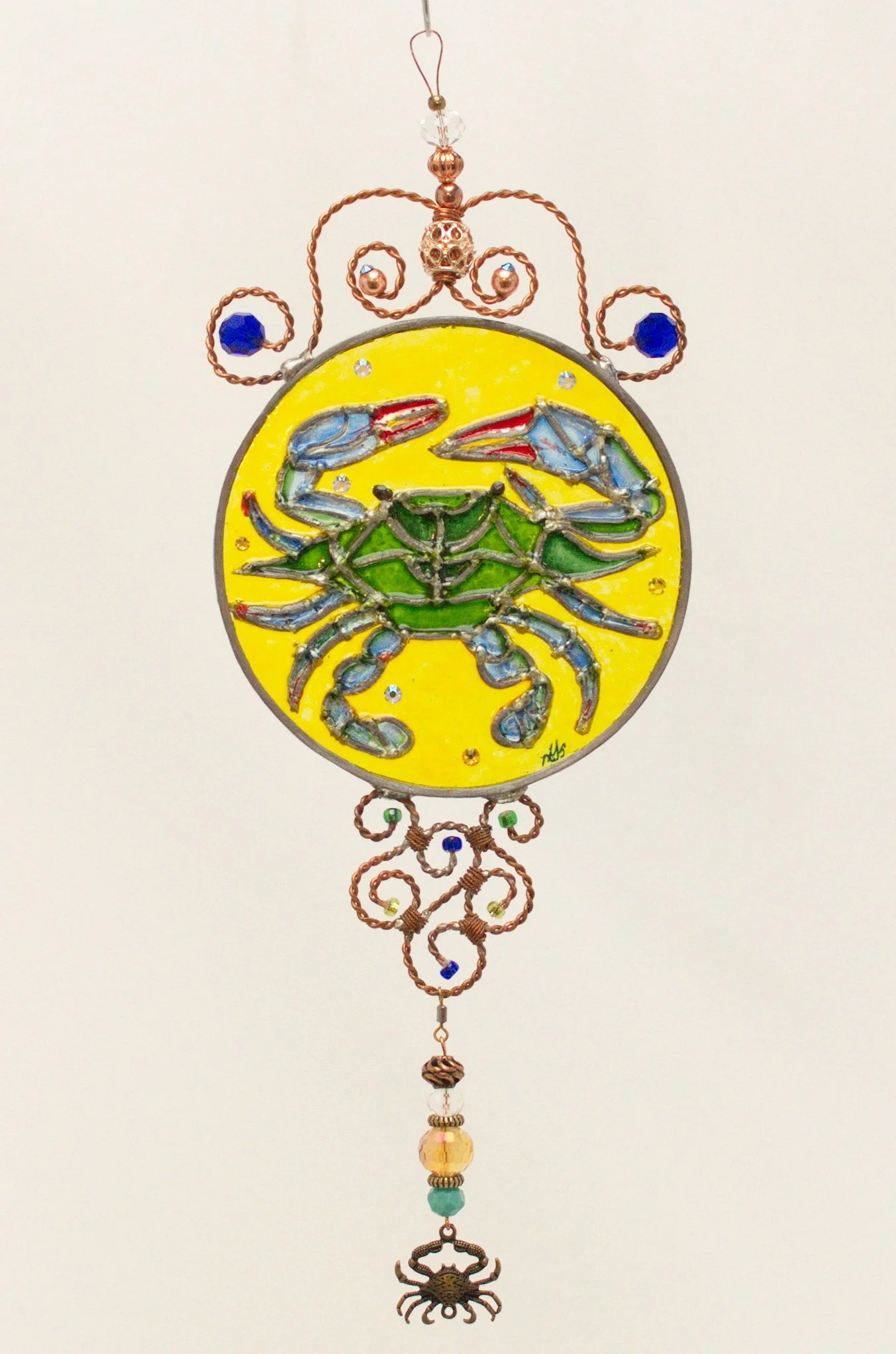 🔴 Sold: 
Blue Crab Illusion Glass by Art Illusions by Young. This vibrant circular piece features a detailed blue crab against a bright yellow background, accented with sparkling crystals and beads. The lively composition celebrates Louisiana’s coas