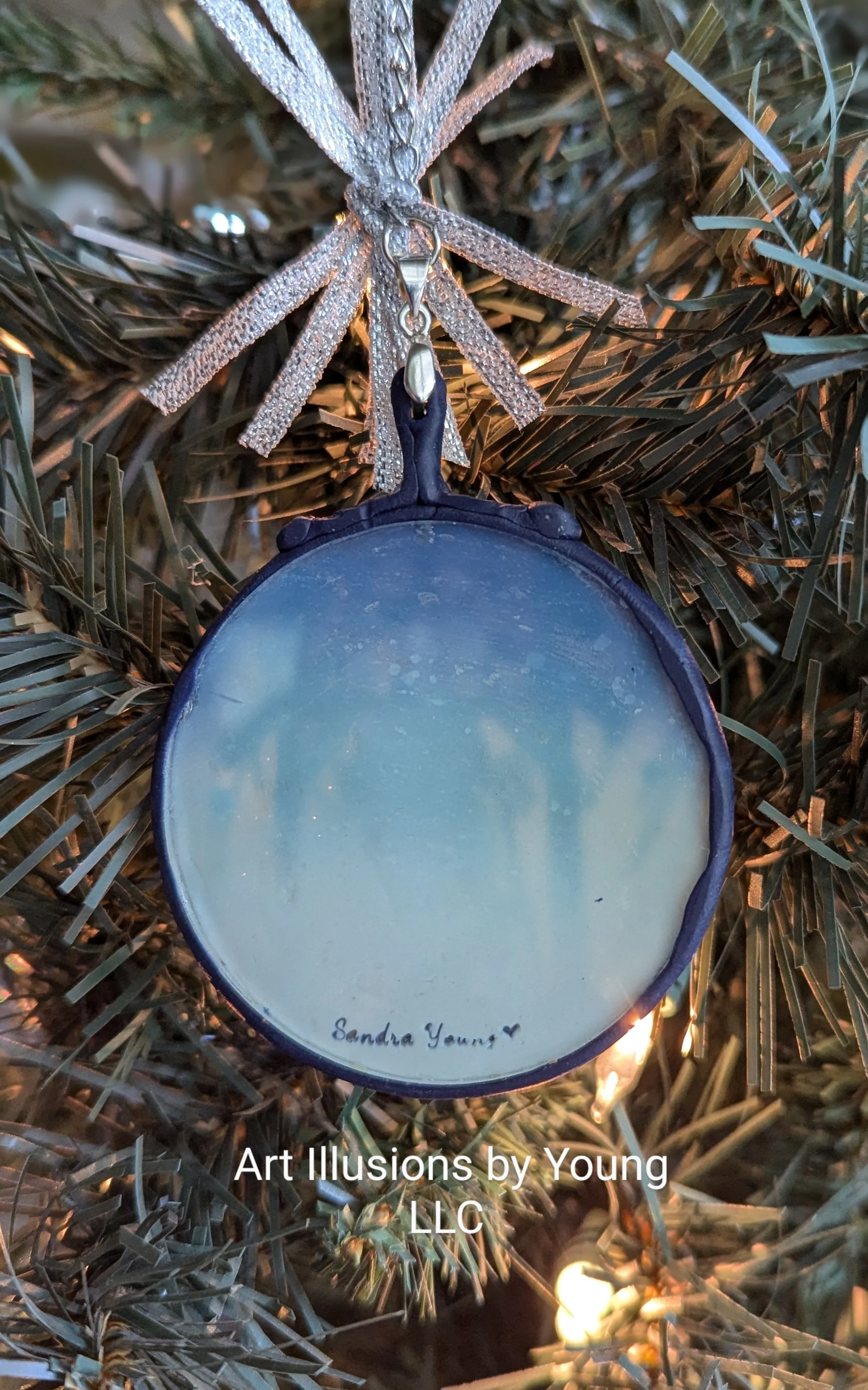 The Nativity Manger Ornament by Art Illusions by Young showing the rear view with artist stamp. The glass backing reveals the gradient midnight-blue background bringing depth and reverence, evoking the peaceful wonder of that first Christmas night.