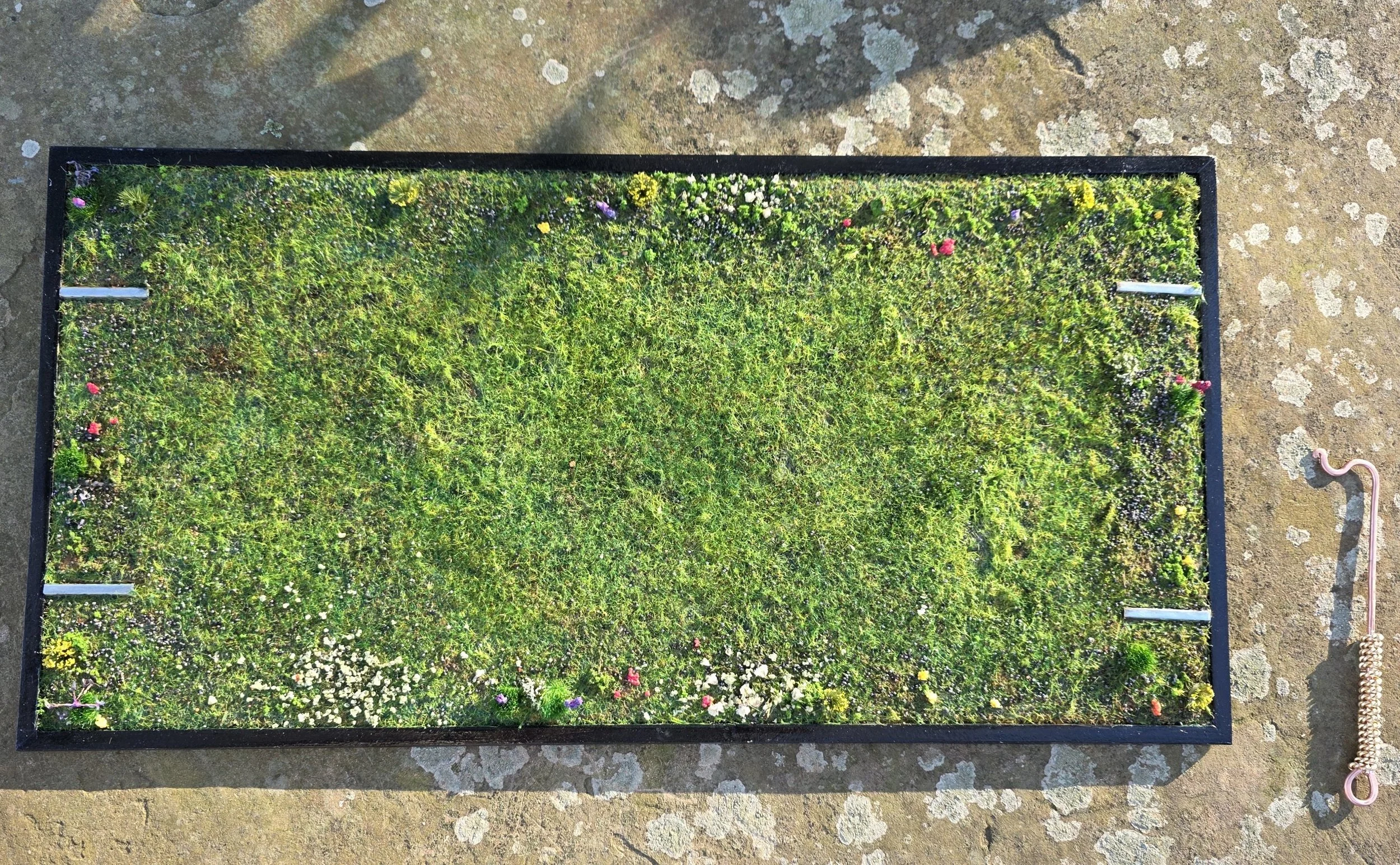 Close-up of the handcrafted grassy base with realistic flocking and wildflower details on the New Orleans streetcar diorama. Textural element of the mixed media functional art by Art Illusions by Young.