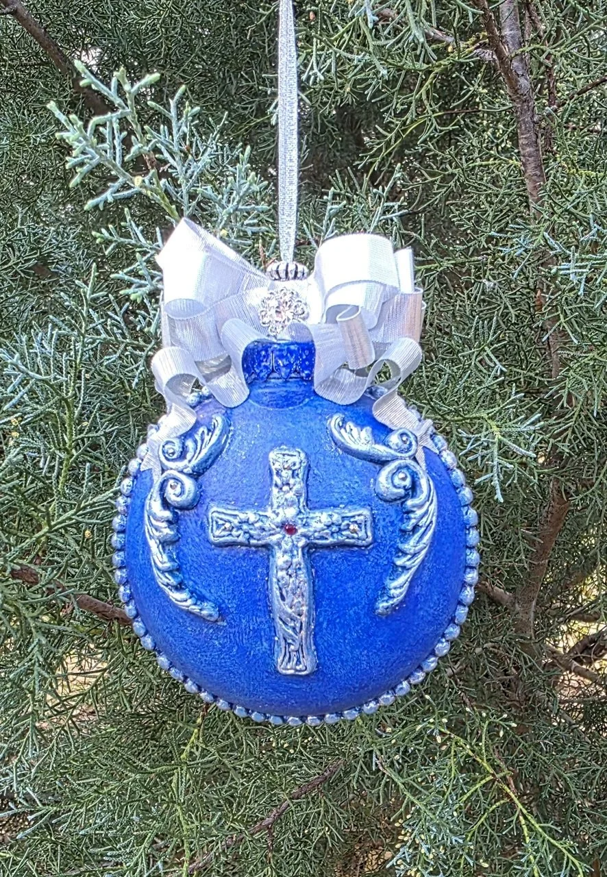Azure Blue Cross Ornament – Sacred Elegance in Blue by Art Illusions by Young from Folsom, Louisiana. A radiant deep azure blue orb centers on an ornate silver cross adorned with intricate filigree and scrollwork that catches light with every movemen
