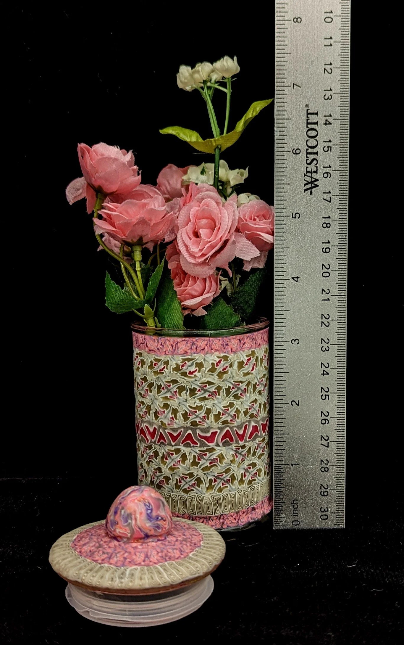 Vertical measurement view of the Floral Lace Trinket Jar by Art Illusions by Young holding a bouquet of pink roses. The hand-sculpted lace-like patterns in soft cream with pink bands and gold accents highlight the intricate floral and geometric desig