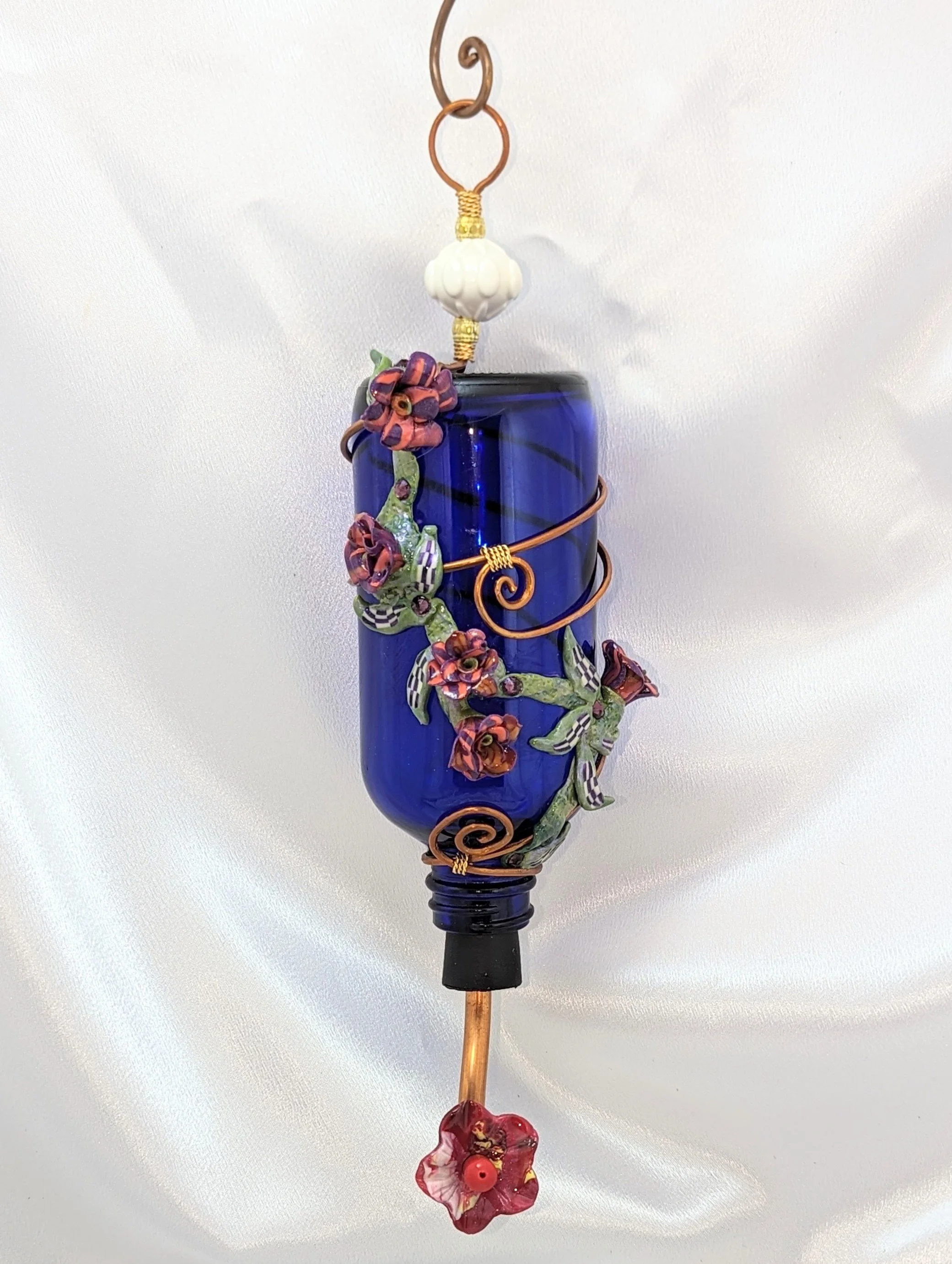 🔴 Sold: 
Multicolor Floral Cobalt Hummingbird Feeder by Art Illusions by Young, Folsom, Louisiana. This deep blue glass bottle is transformed into a vibrant hummingbird feeder through abundant hand-sculpted polymer clay flowers in bright pinks, purp
