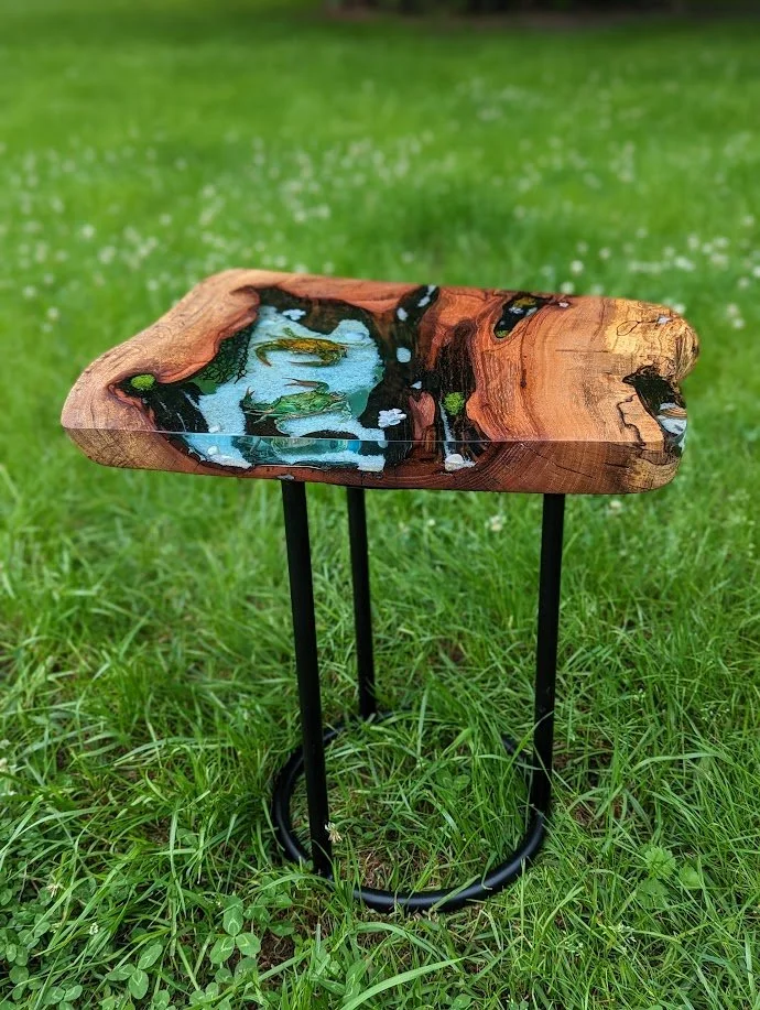🟢 Available :
Magnolia Blue Crab Tide Pool Table by Art Illusions by Young. Real taxidermy blue crabs, sand, seashells, and netting are embedded in clear epoxy poured into live-edge magnolia wood slab. Finished with Rubio Monocoat and mounted on a b