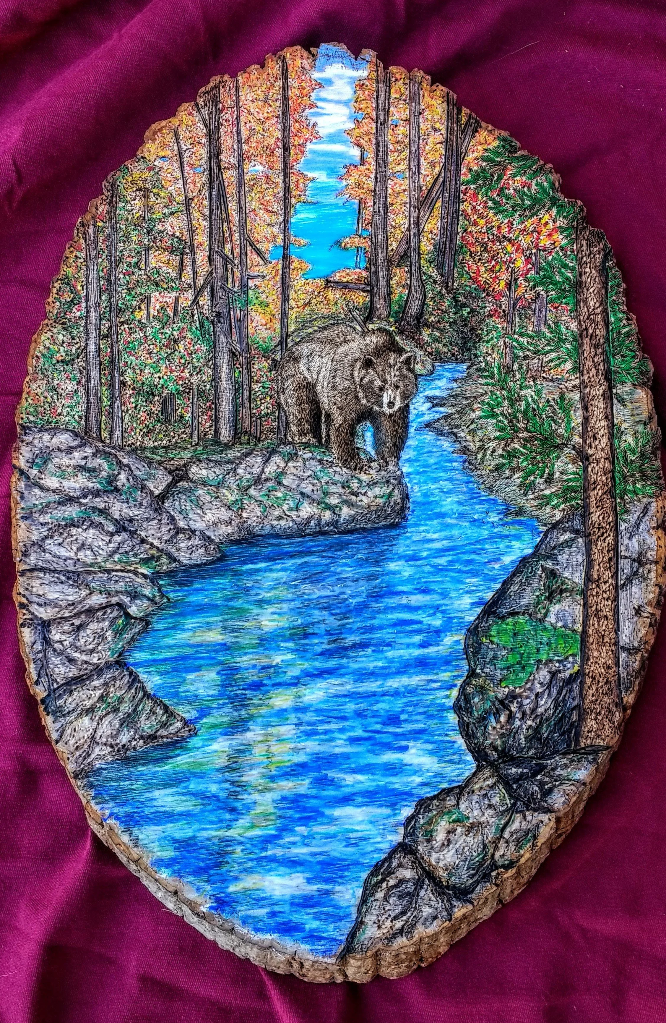 🔴 Sold:
Last Fall Stroll Through the Forest Pyrography by Art Illusions by Young, Folsom, Louisiana. This serene woodburn on a natural wood slice captures a majestic bear taking a leisurely stroll along a rocky stream bank during autumn. Vibrant fal