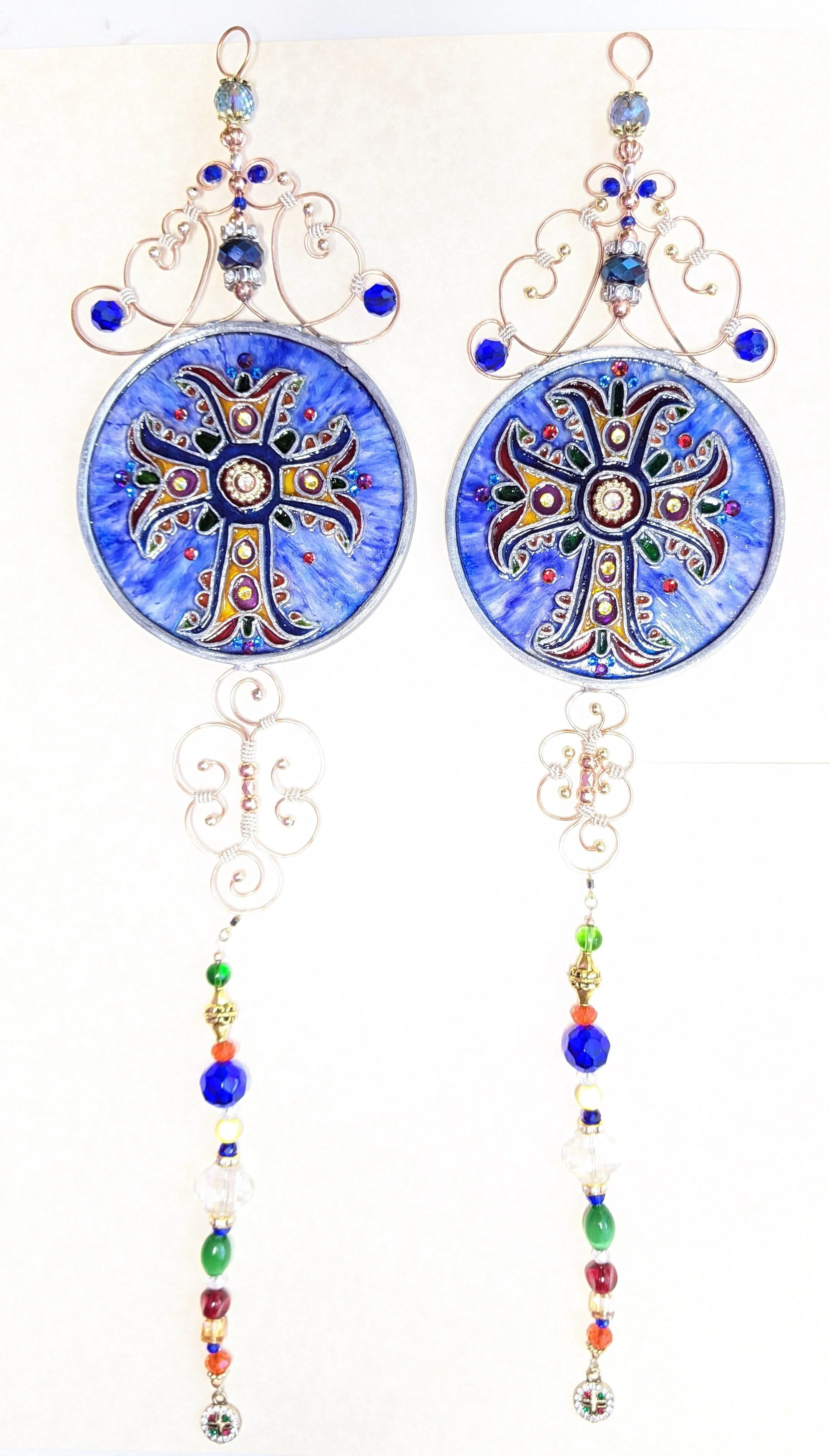 🔴 Sold: 
Crosses Illusion Glass by Art Illusions by Young. A pair of elegant circular suncatchers featuring ornate crosses with intricate bead and crystal accents. The spiritual designs glow with deep blues and metallic tones, offering timeless beau