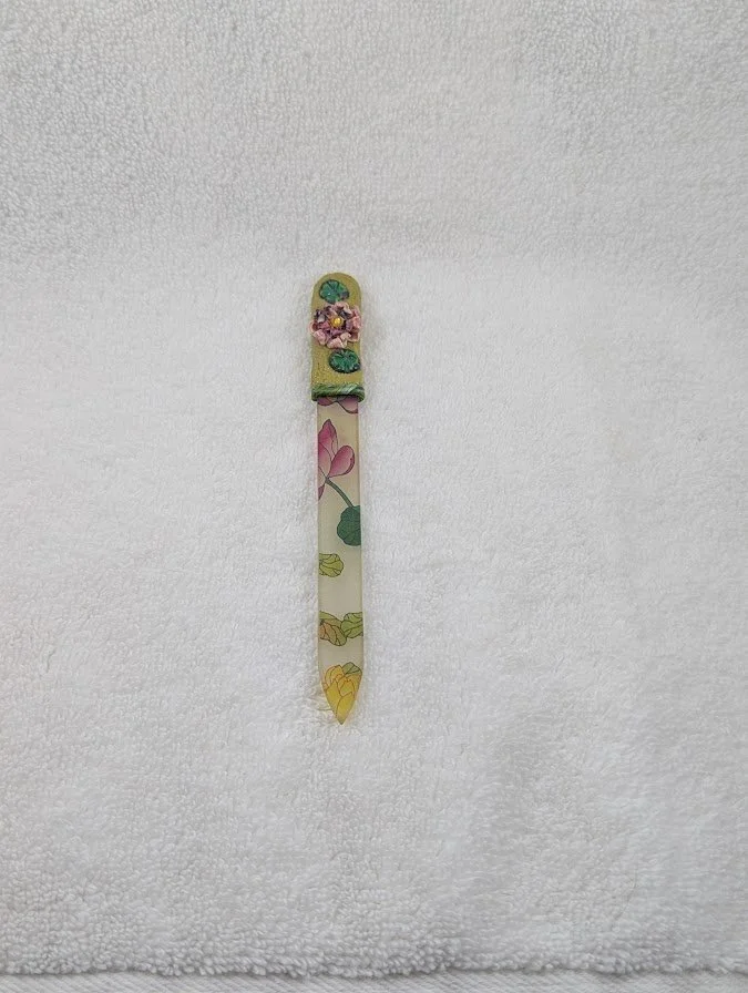 🔴 Sold: 
Polymer Clay Decorated Glass Fingernail File by Art Illusions by Young, Folsom, Louisiana. This elegant and functional fingernail file features a smooth glass base adorned with hand-sculpted polymer clay in a delicate lotus flower and lily 
